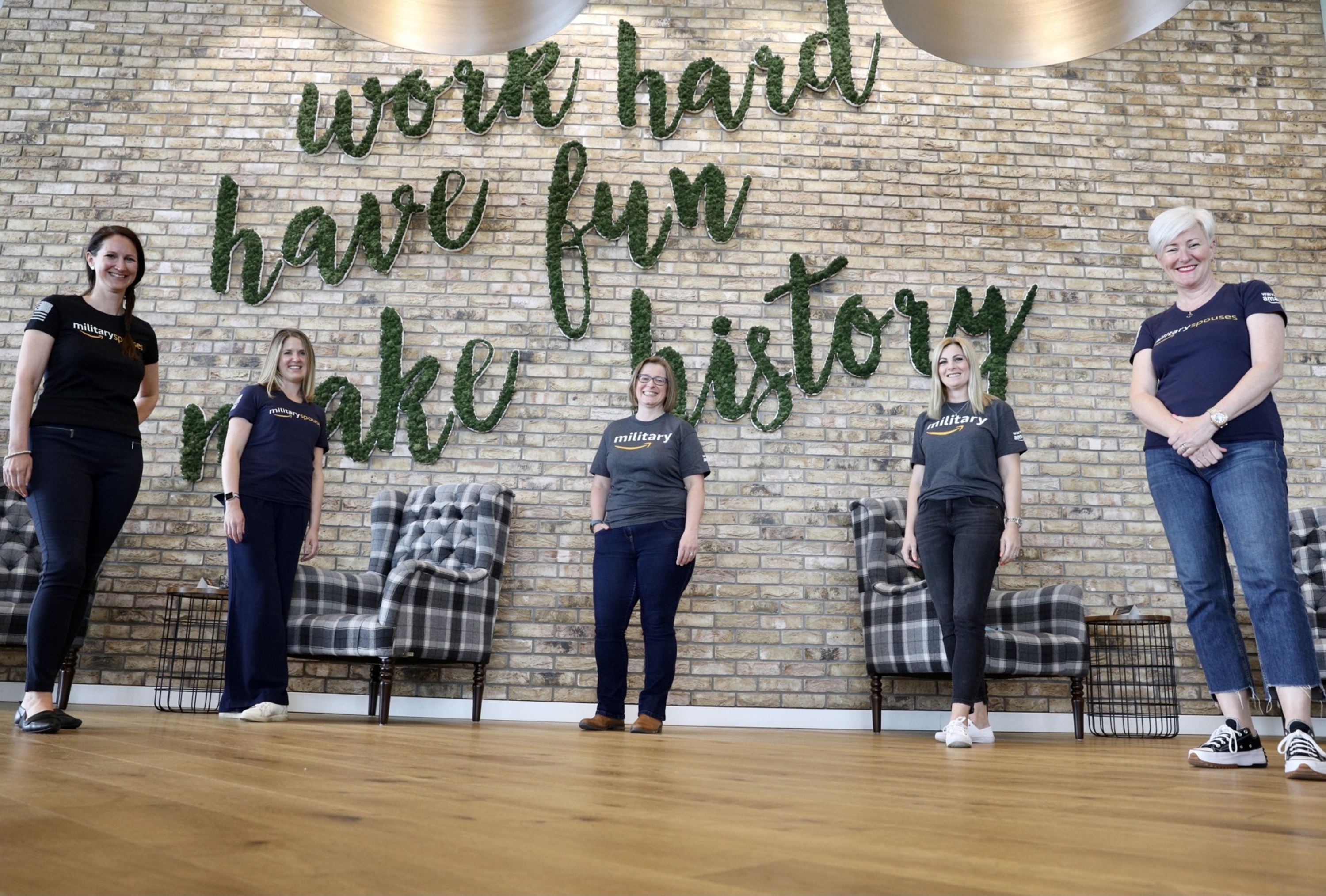 Amazon employees, and ex-veterans from the Warriors@ affinity group staniding in front of a sign which reads "work hard, have fun, make history".