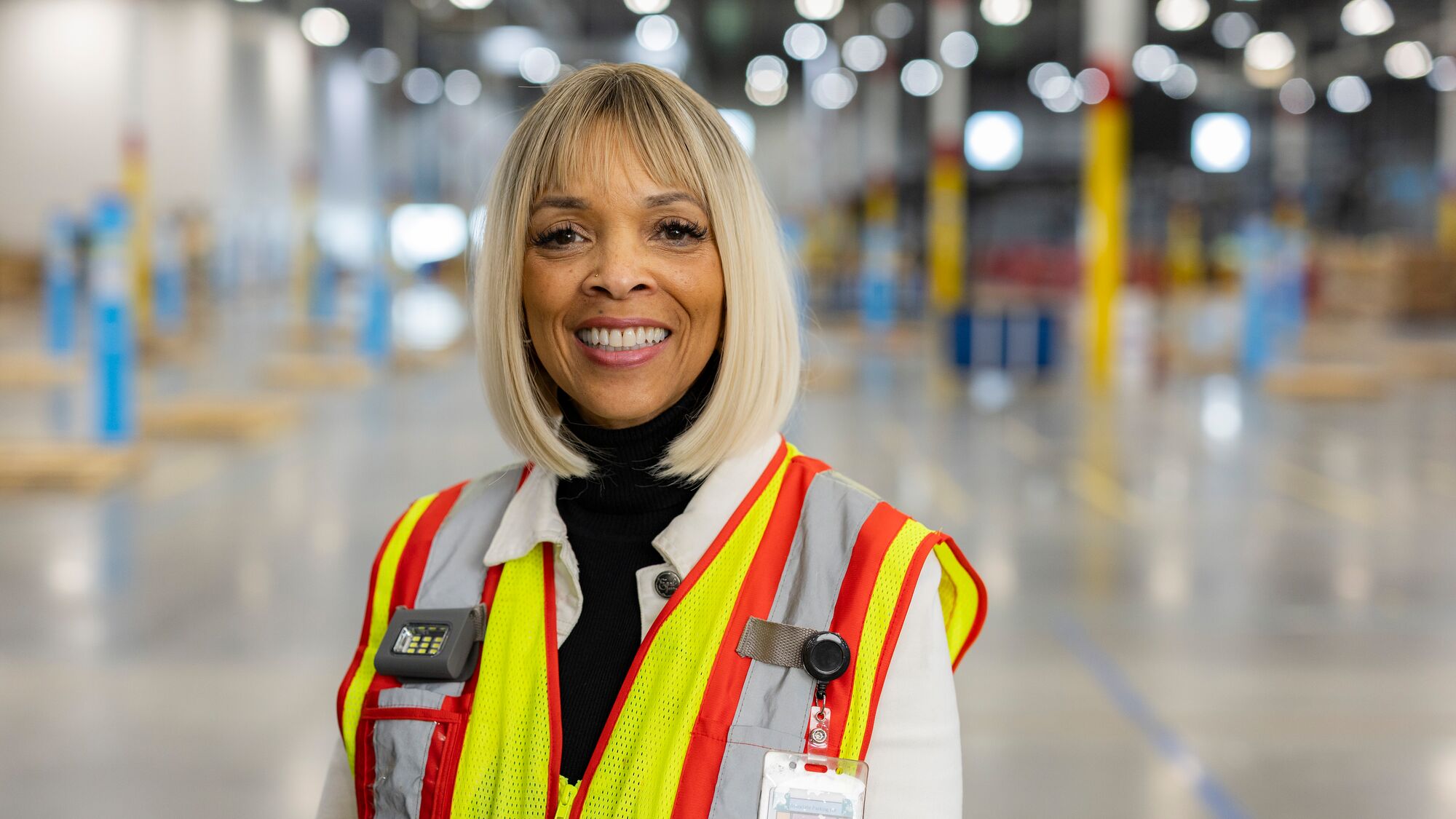 Smiling employee wearing high-visibility gear in large facility