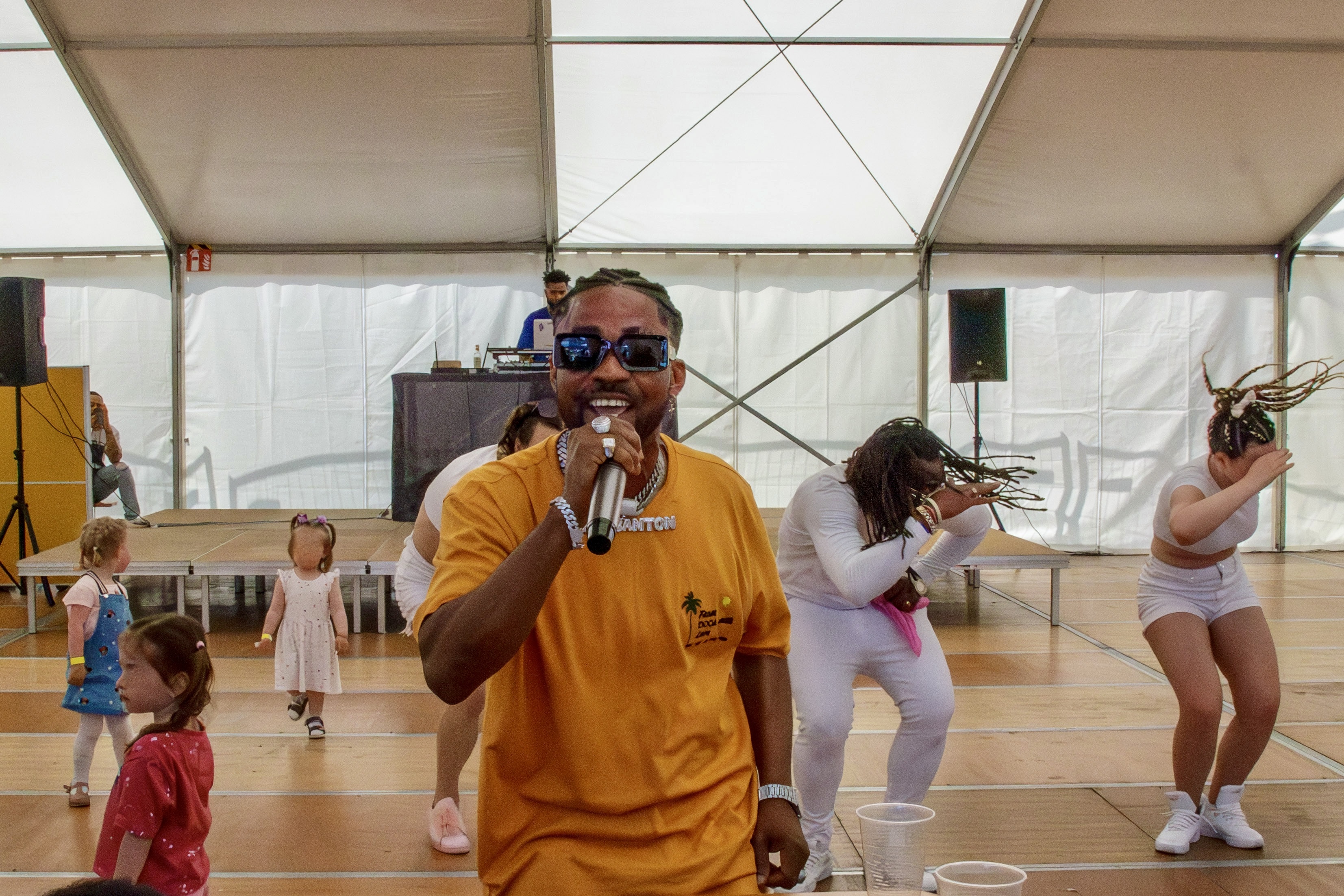 Sommerfest im Amazon Logistikzentrum Graben: Man sieht David mit Mikrofon im Festzelt und im Hintergrund Tänzerinnen.