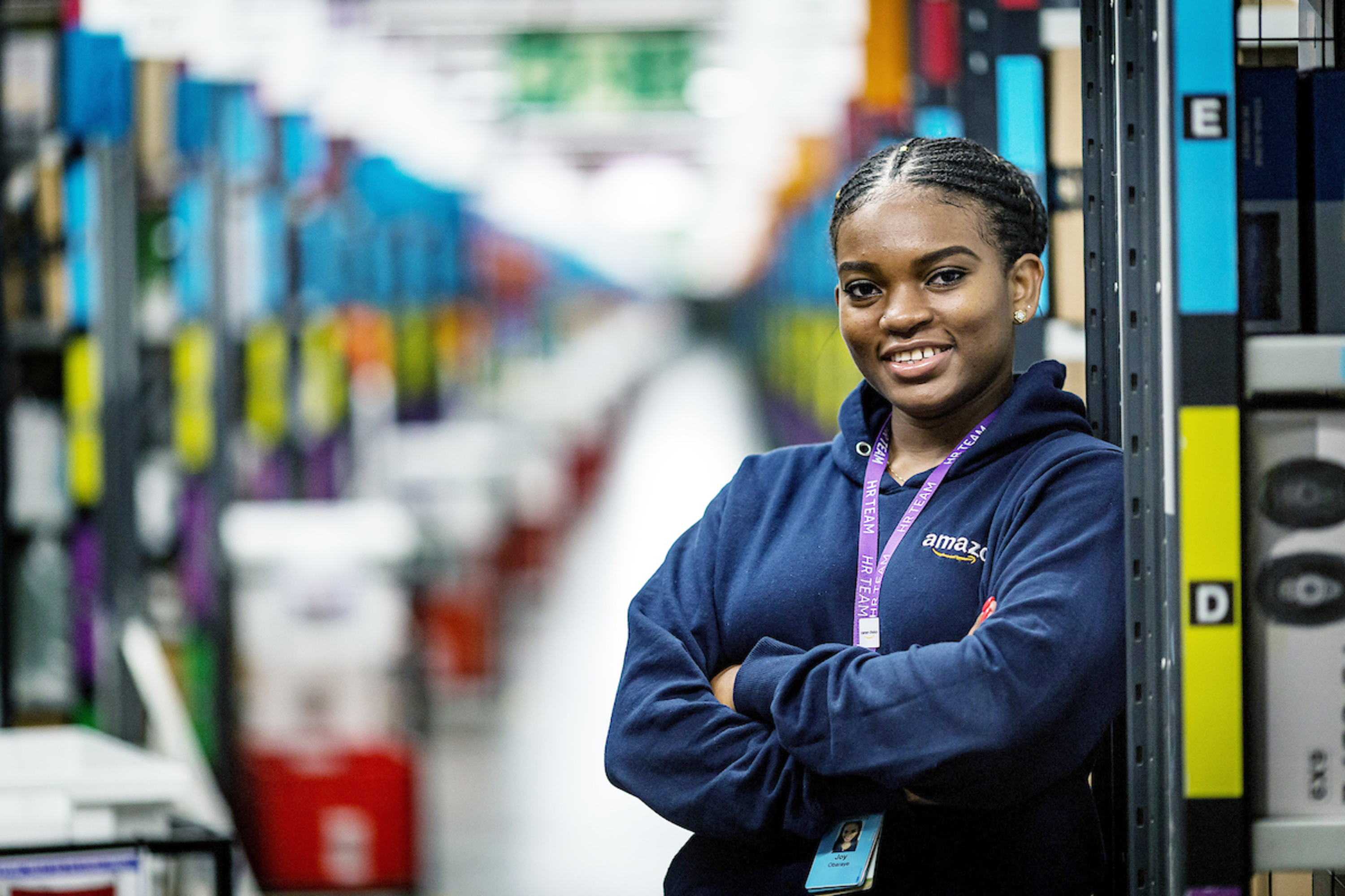 Joy Abaraye standing with her arms crossed in a fulfilment centre.