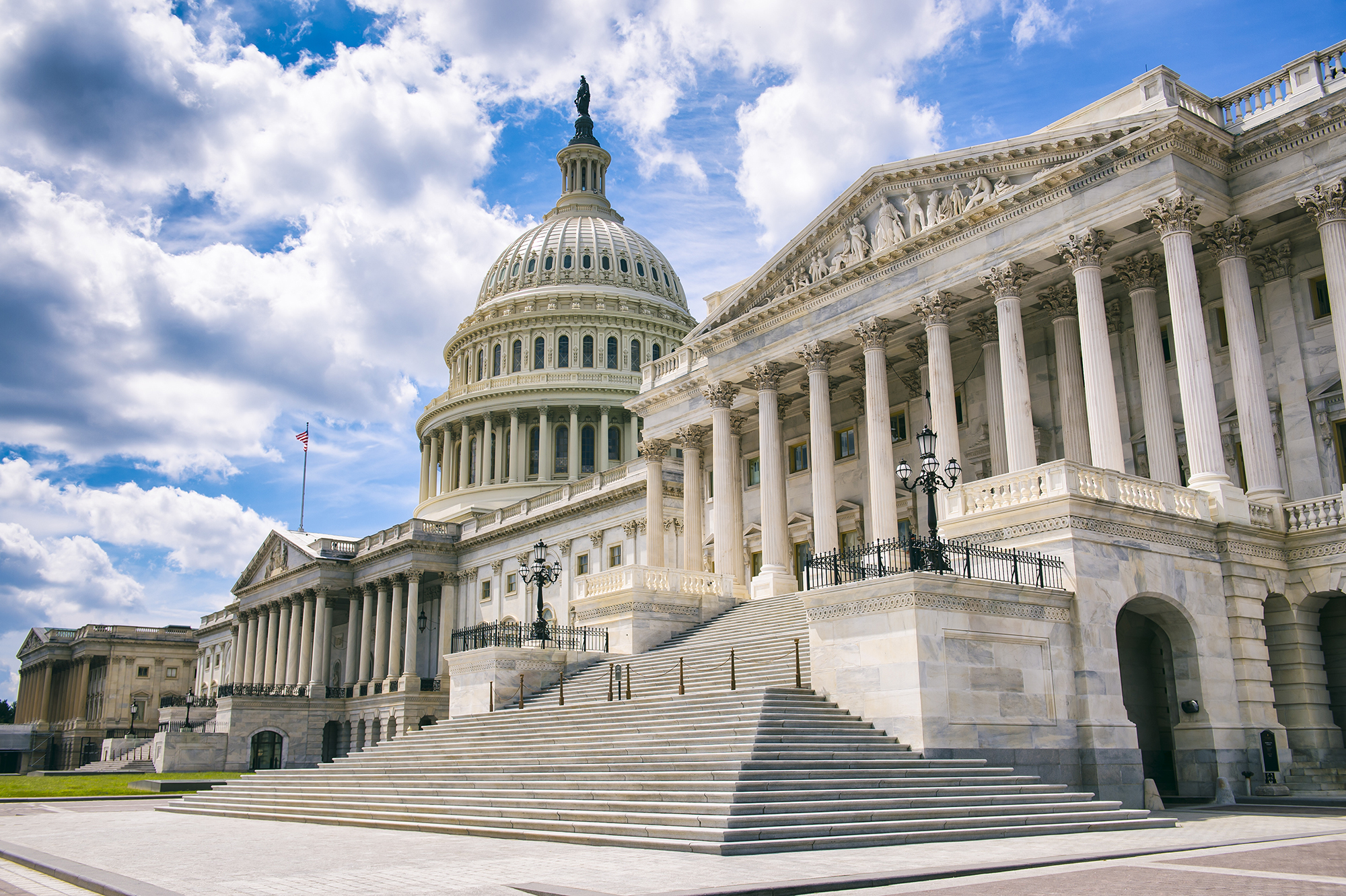 The U.S. Capitol, shown with no people in the image, in front of a blue sky with some visible clouds