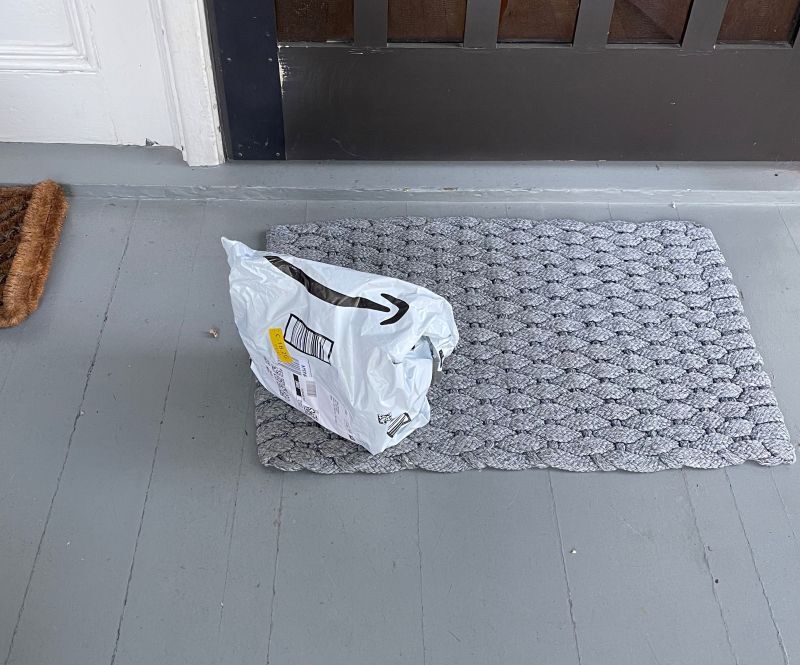 An Amazon packaged sits in front of a doorstep.