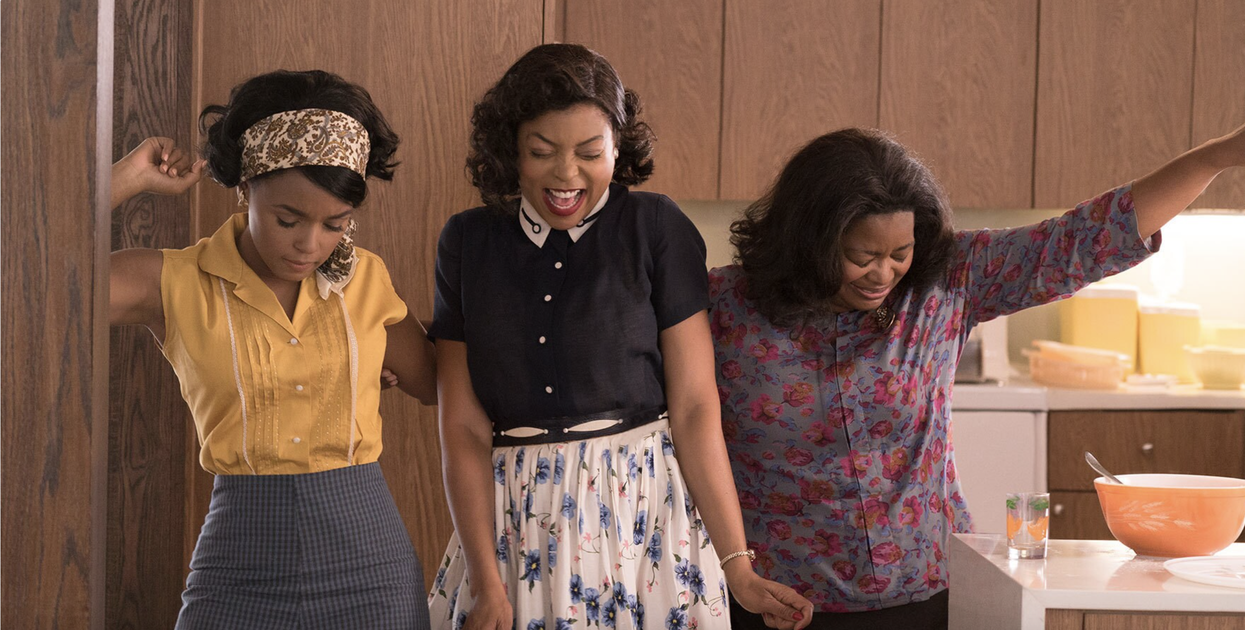 Three women standing in a kitchen celebrating 