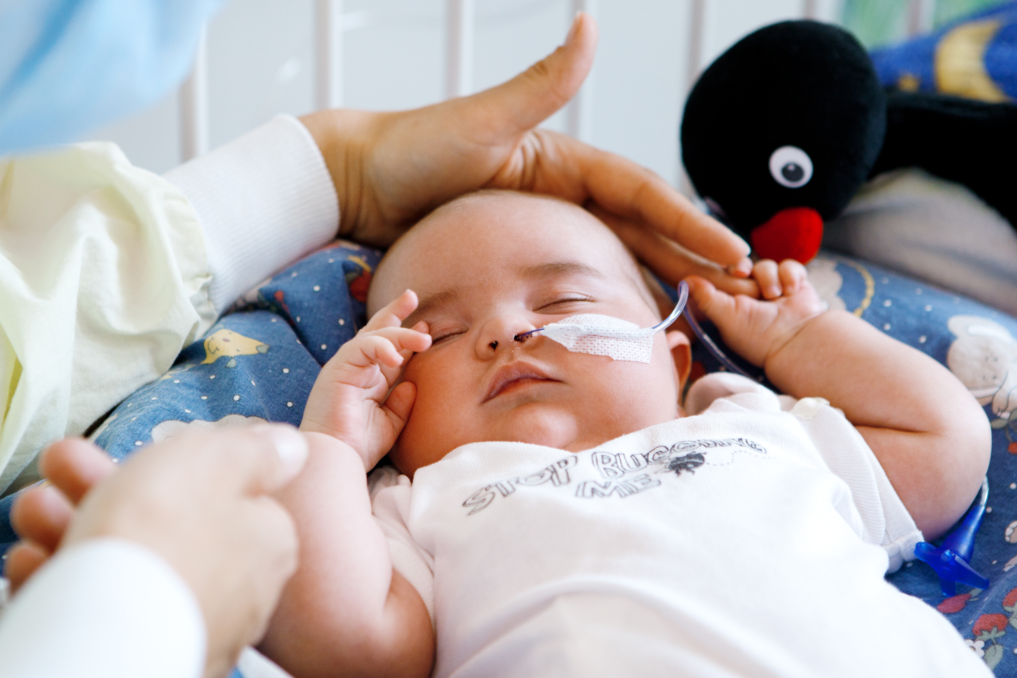 Eine Mutter legt schützend ihre Hand über den Kopf ihres kranken Babys
