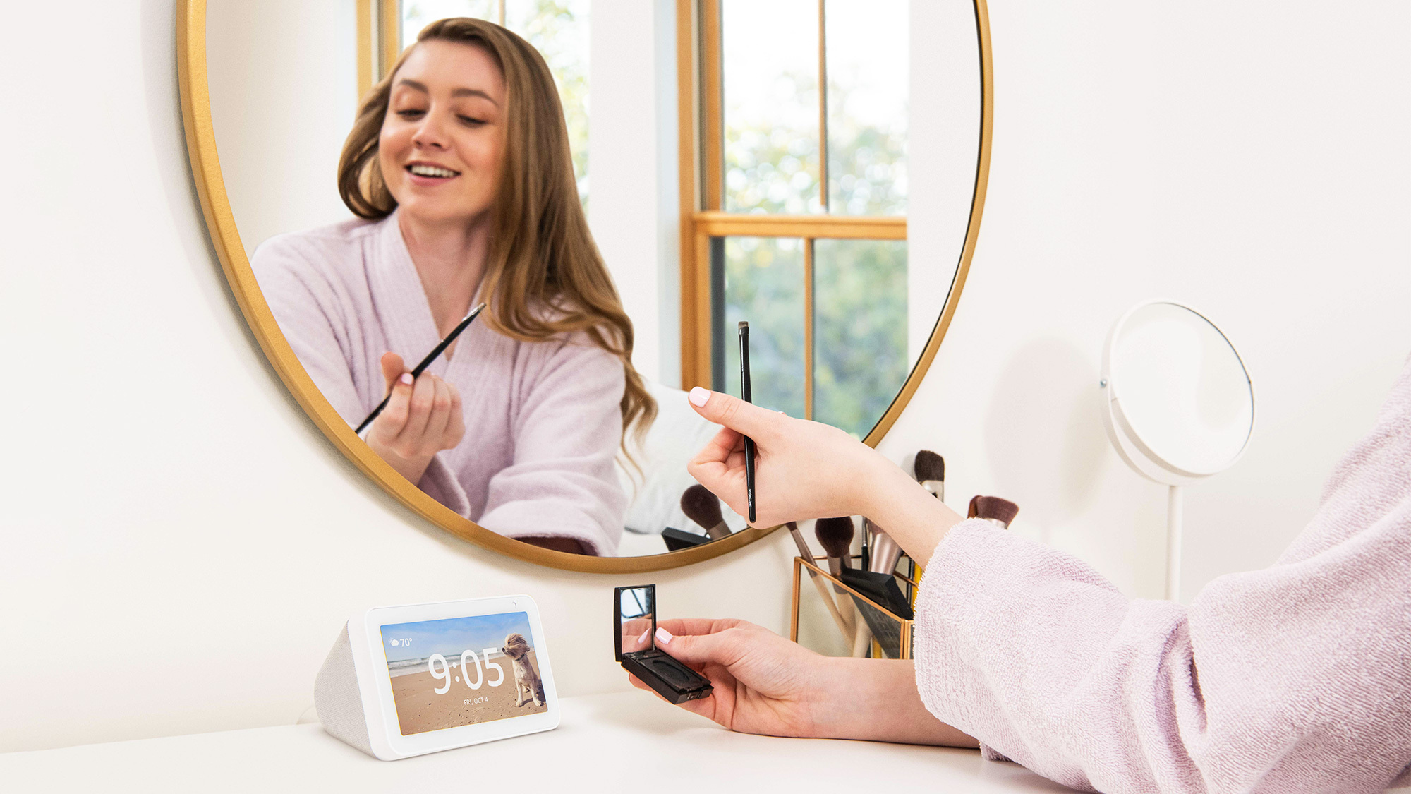 A woman looking at an Alexa device while doing her makeup.