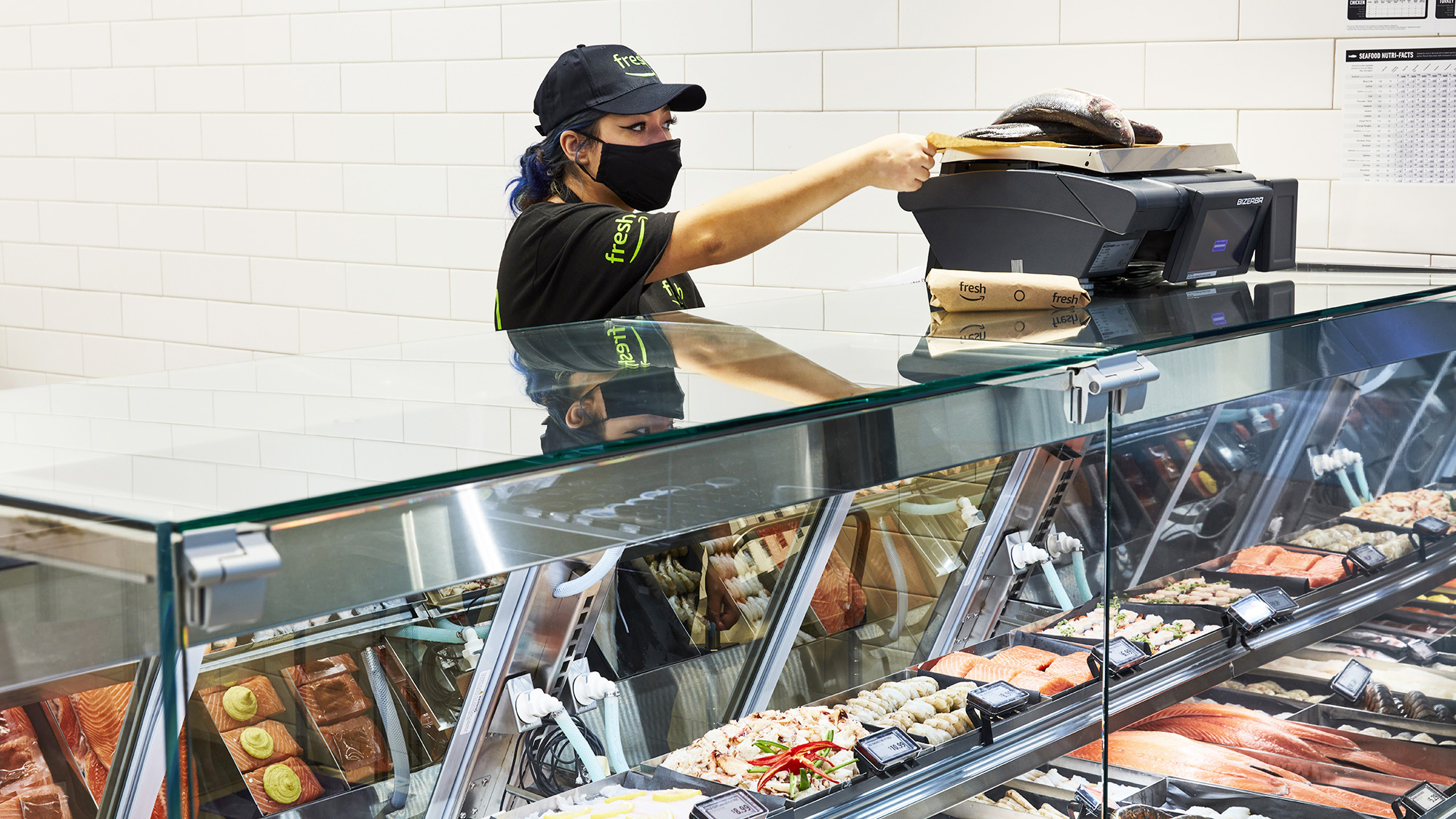 An image of a woman working at a counter in an Amazon Fresh store.