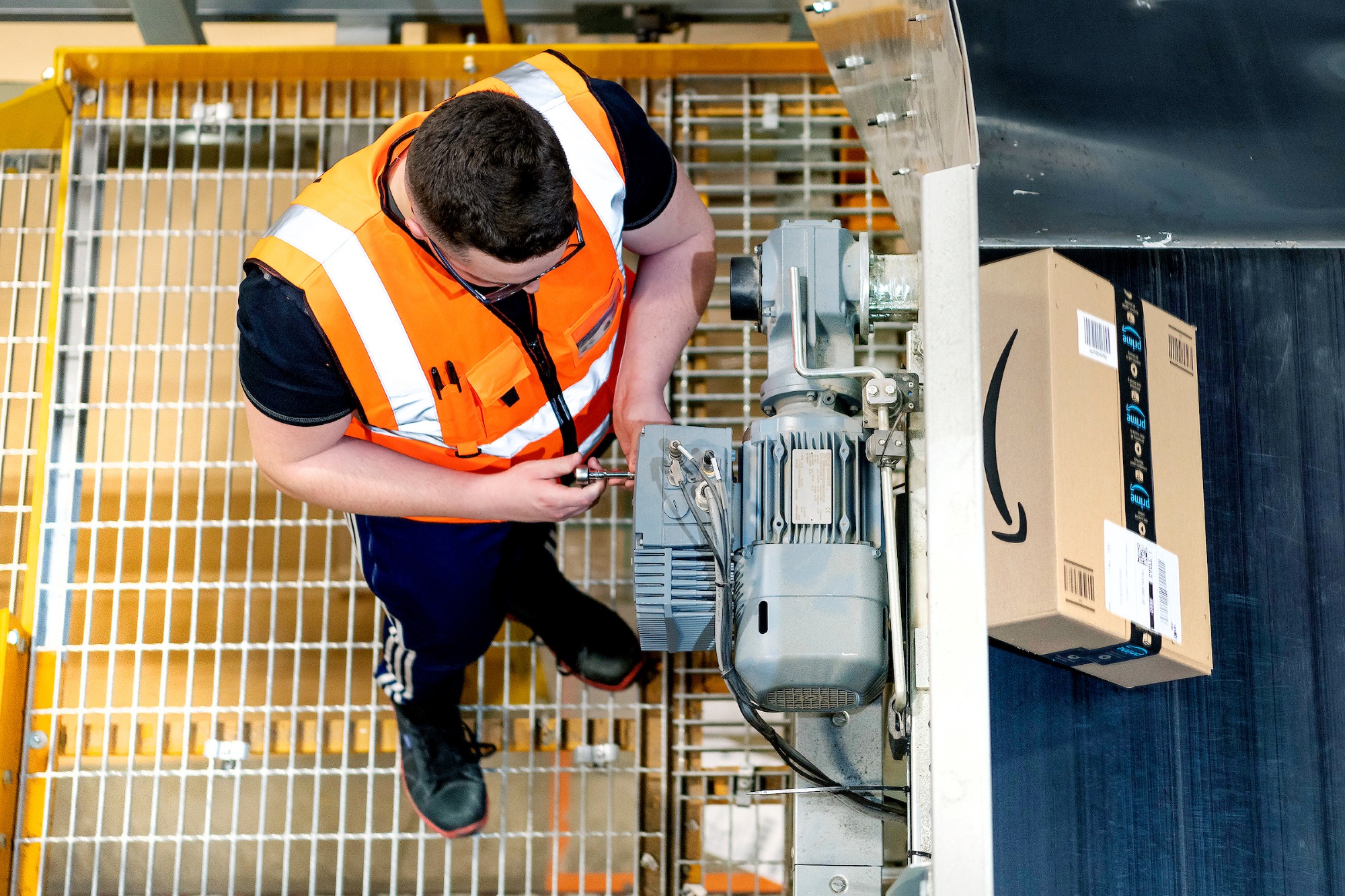 Worker in safety vest inspecting machinery in warehouse