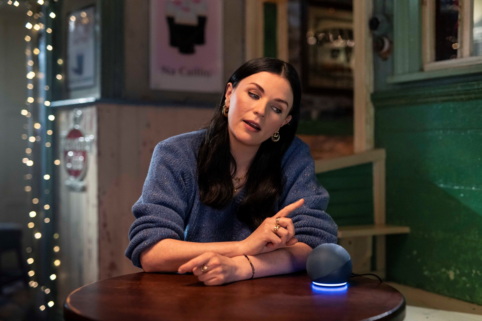 Aisling Bea sitting at a table talking to Alexa with an Amazon Echo Device