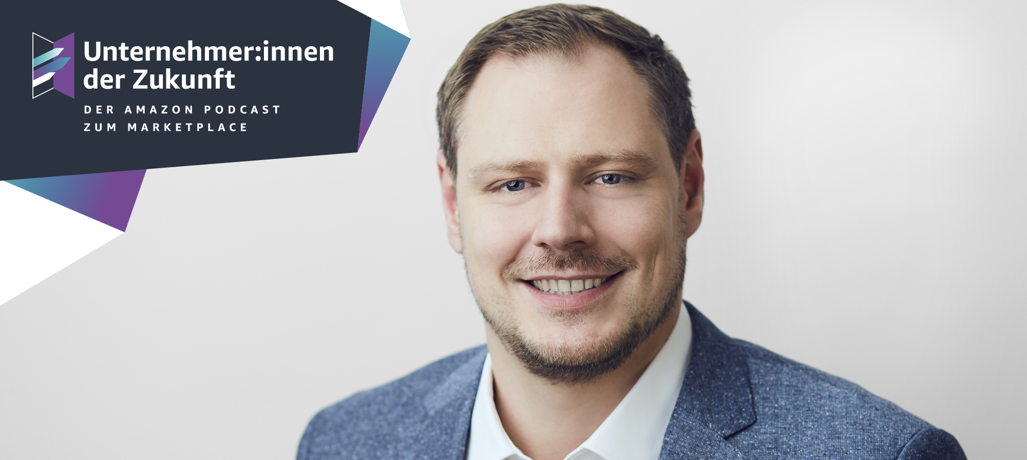Ein Mann mit braunen Haaren und einem kurzen braunen Bart lächelt in die Kamera.