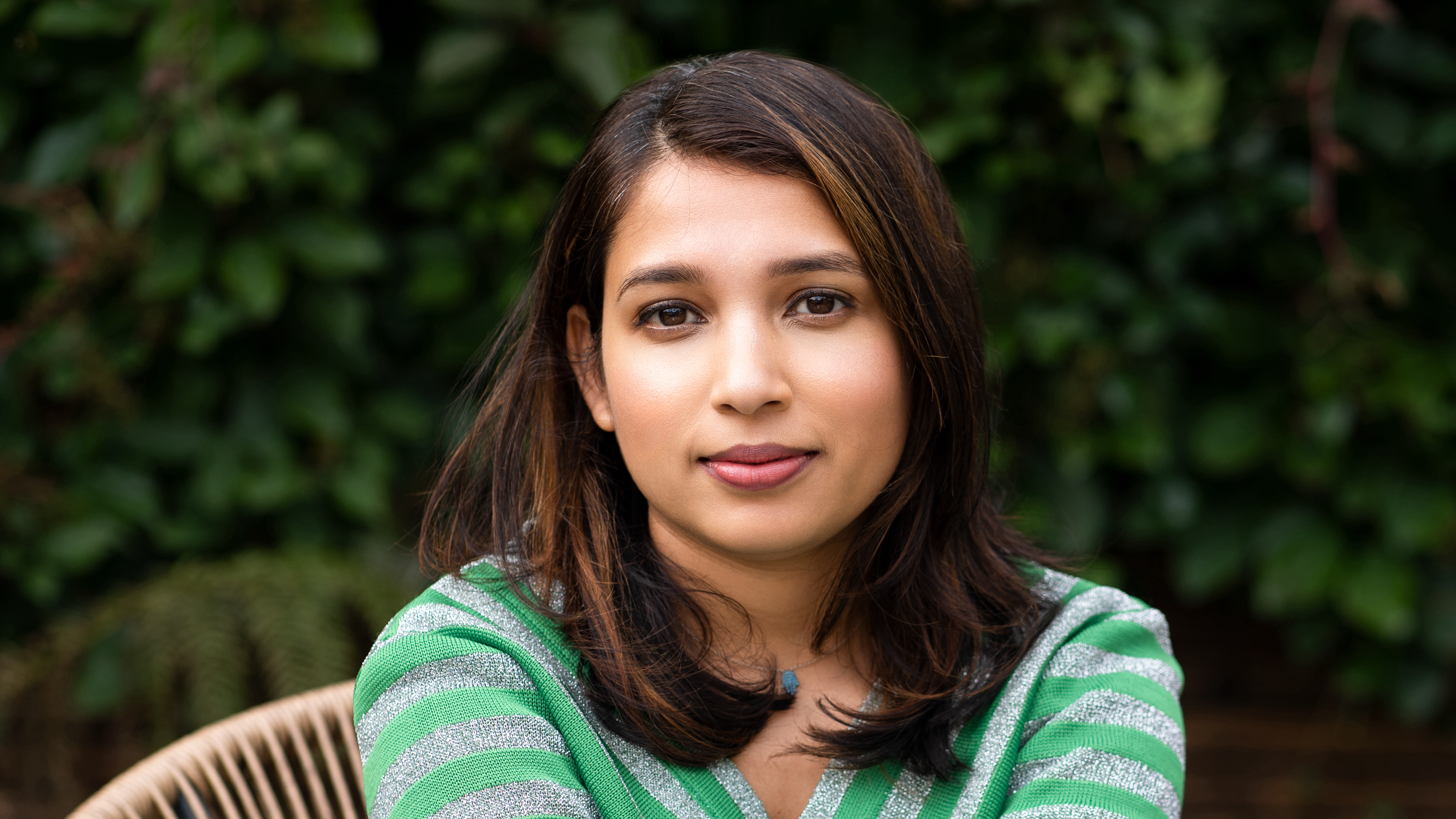 An image of Anjana Anand sat on a chair