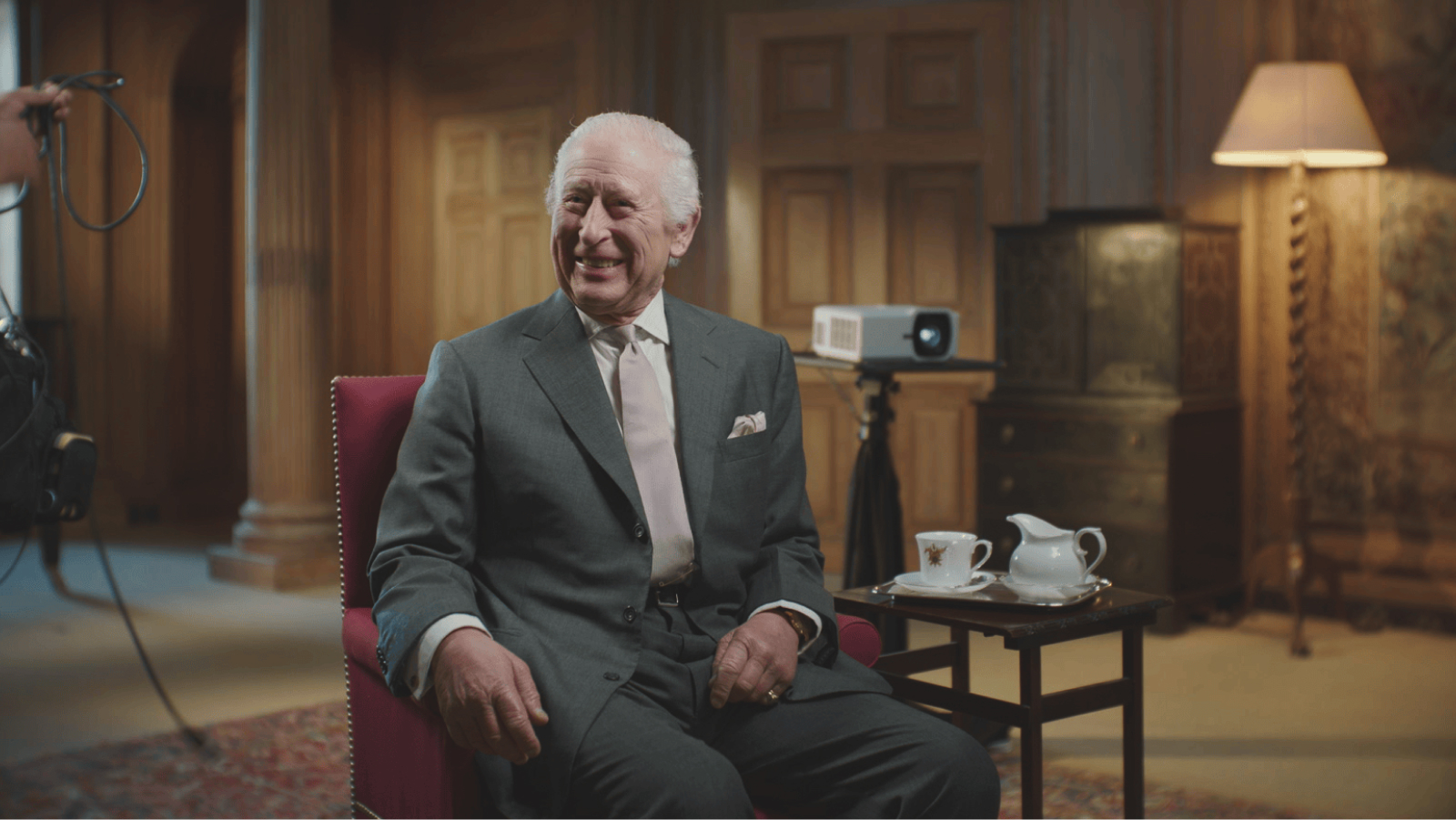 King Charles in suit smiling during interview setting