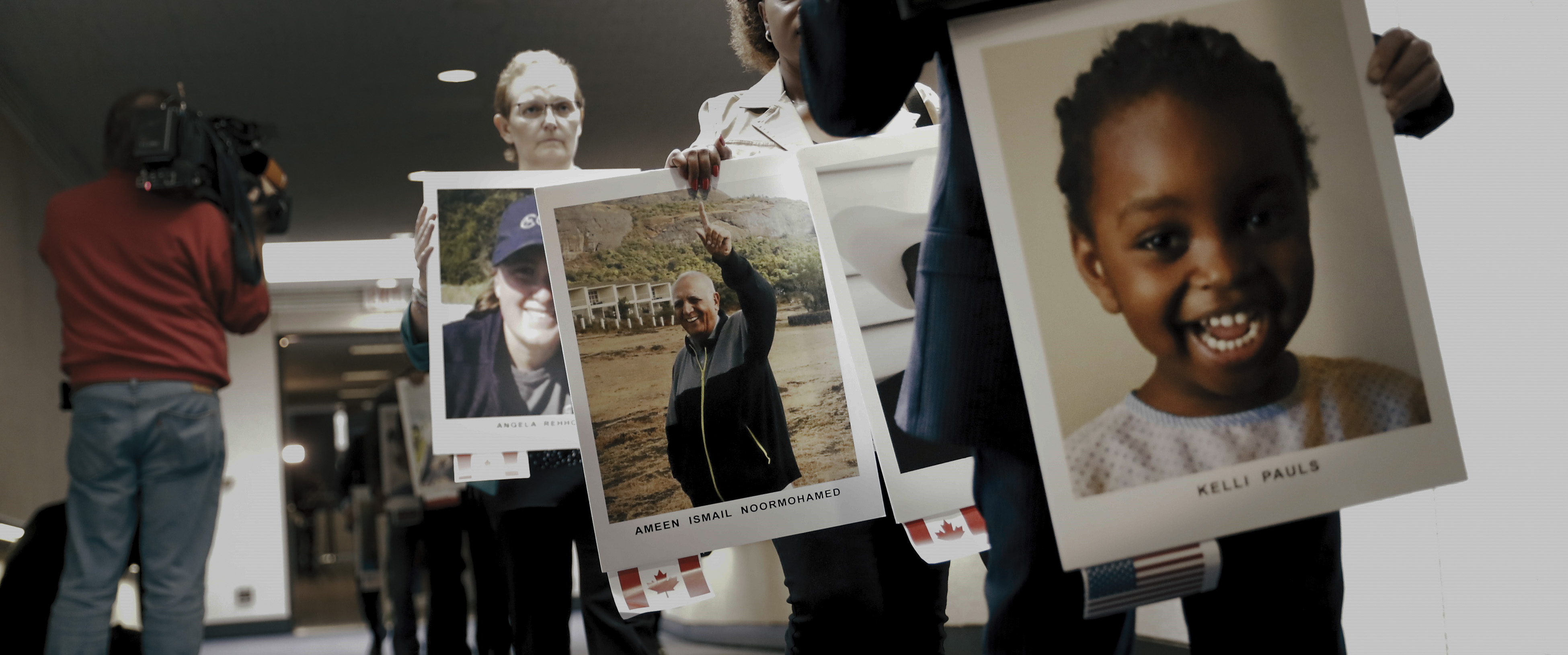 Personen, die bei einer Veranstaltung große Fotos von Personen hochhalten.
