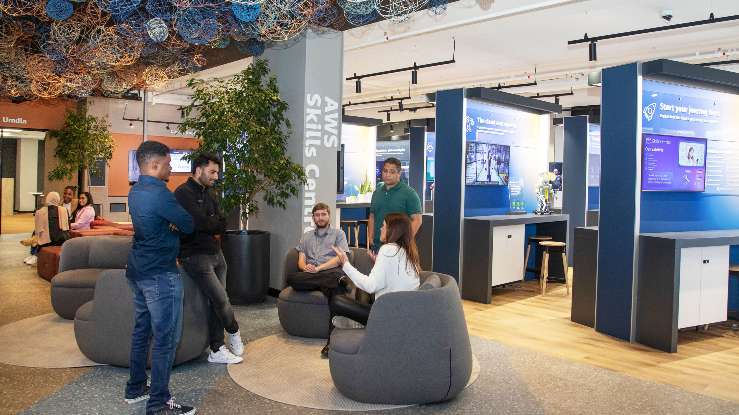 group of adults sitting in chairs and standing around a circle inside the new aws skills center in cape town south africa 