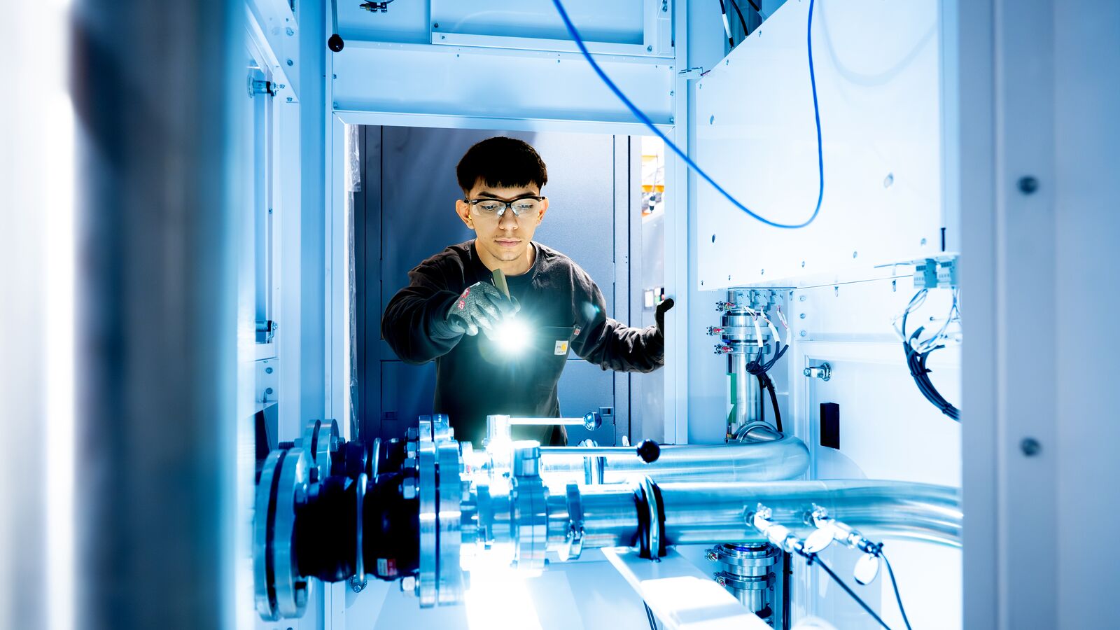 An AWS engineer looking into the new liquid cooling system with a flashlight