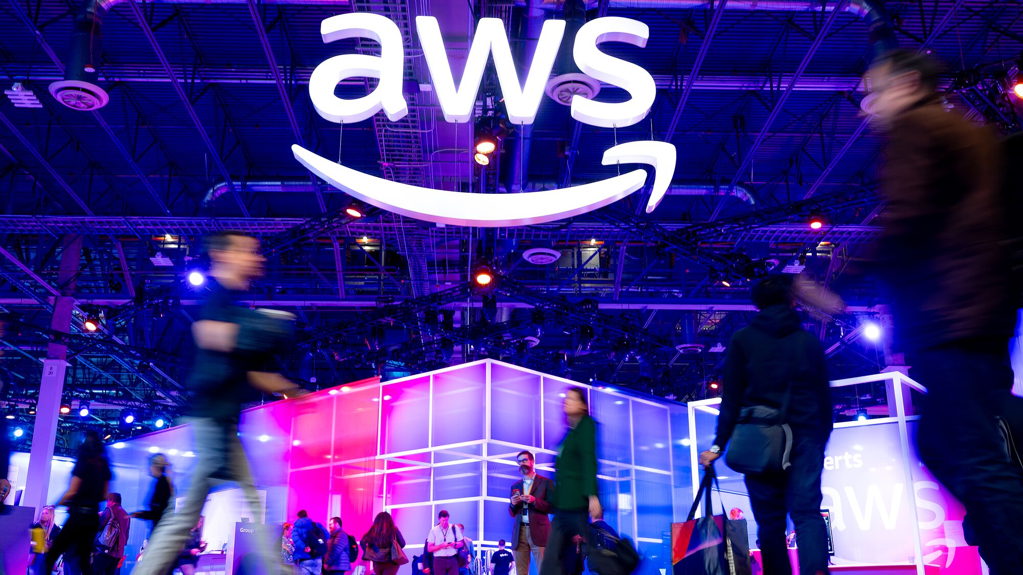 AWS re:Invent AWS logo illuminated above bustling tech conference floor