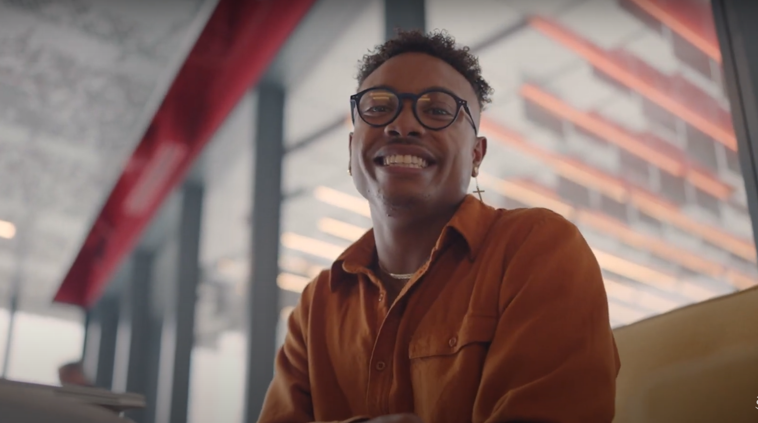 An image of a man smiling at the camera while sitting in an office lobby.