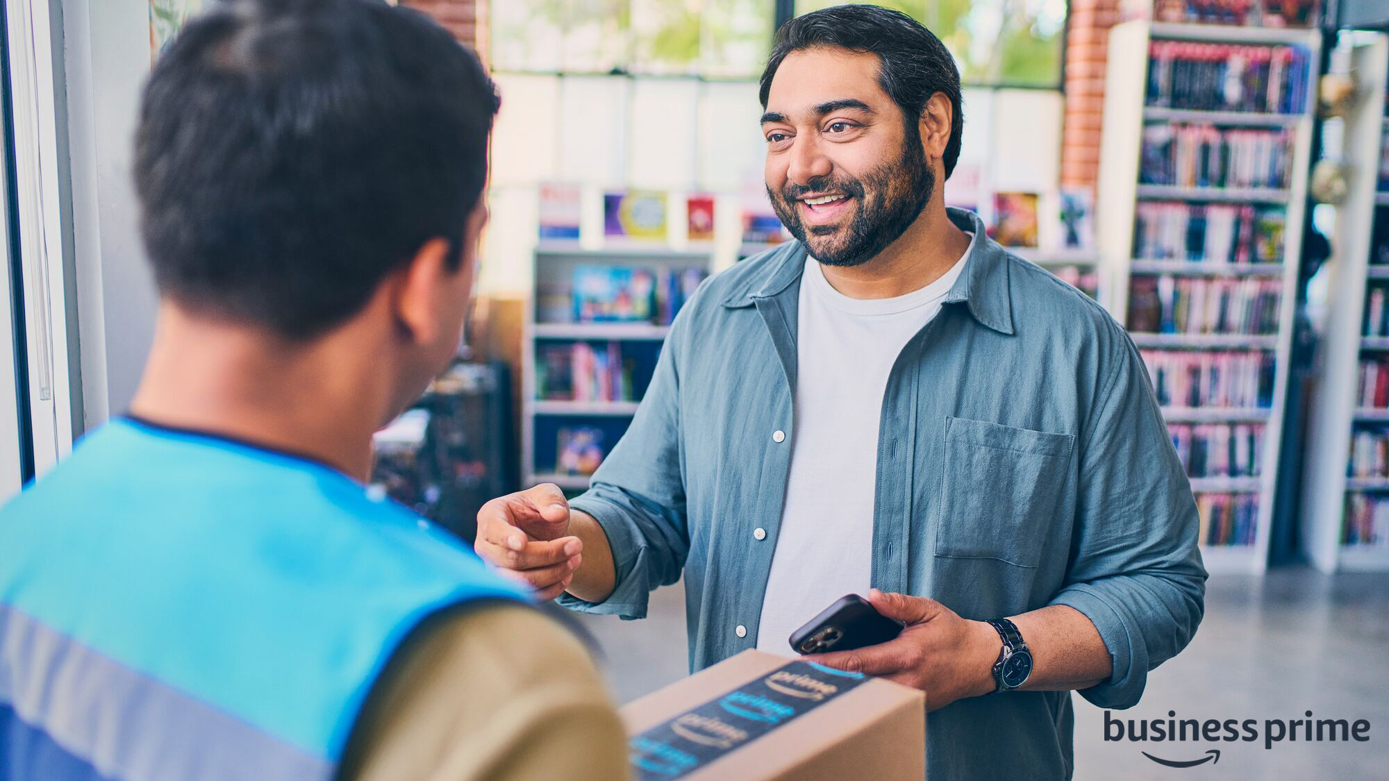 Smiling man receiving package from Amazon delivery person in bookstore