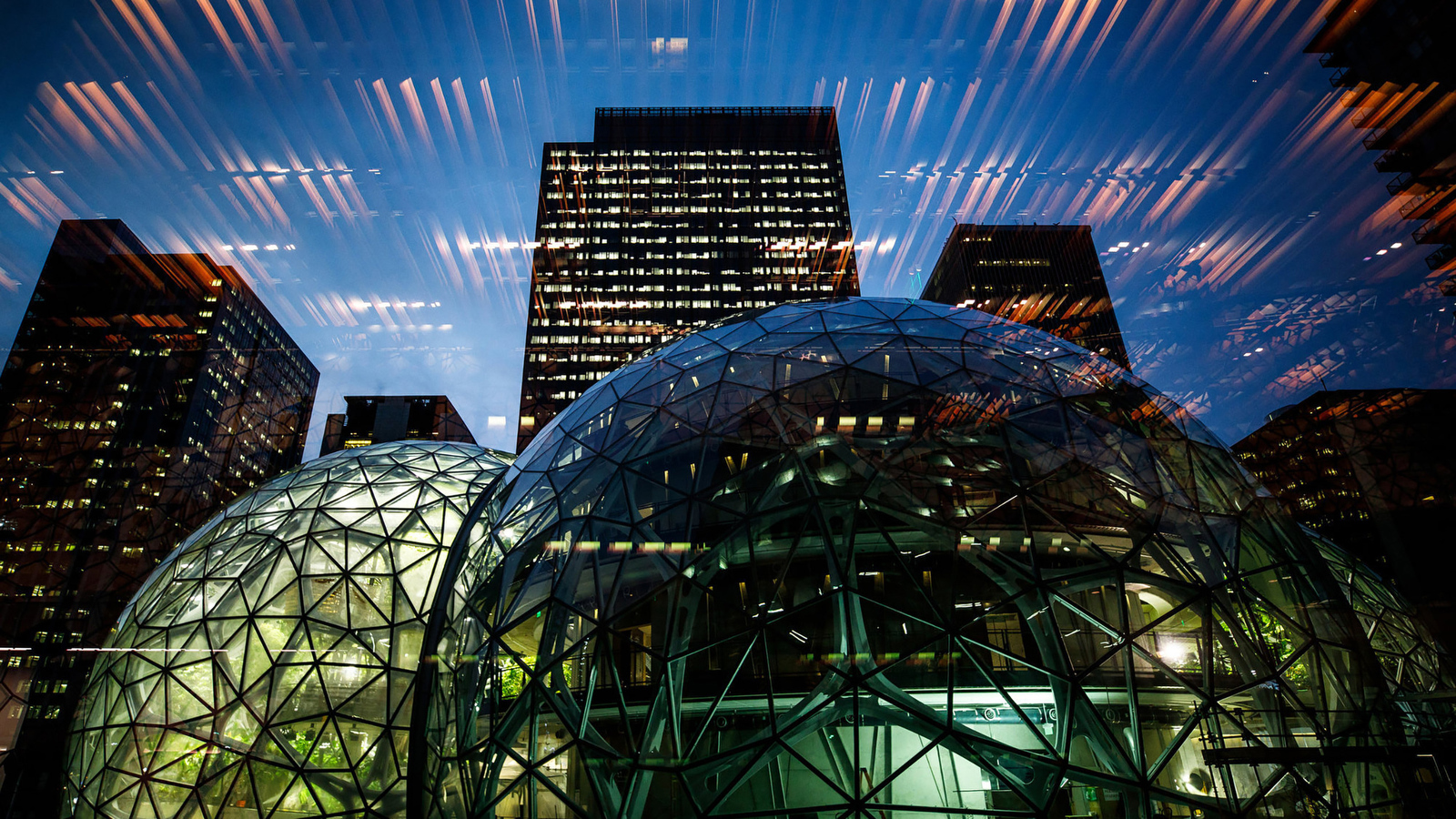 The Spheres illuminated at night with downtown buildings in the background.