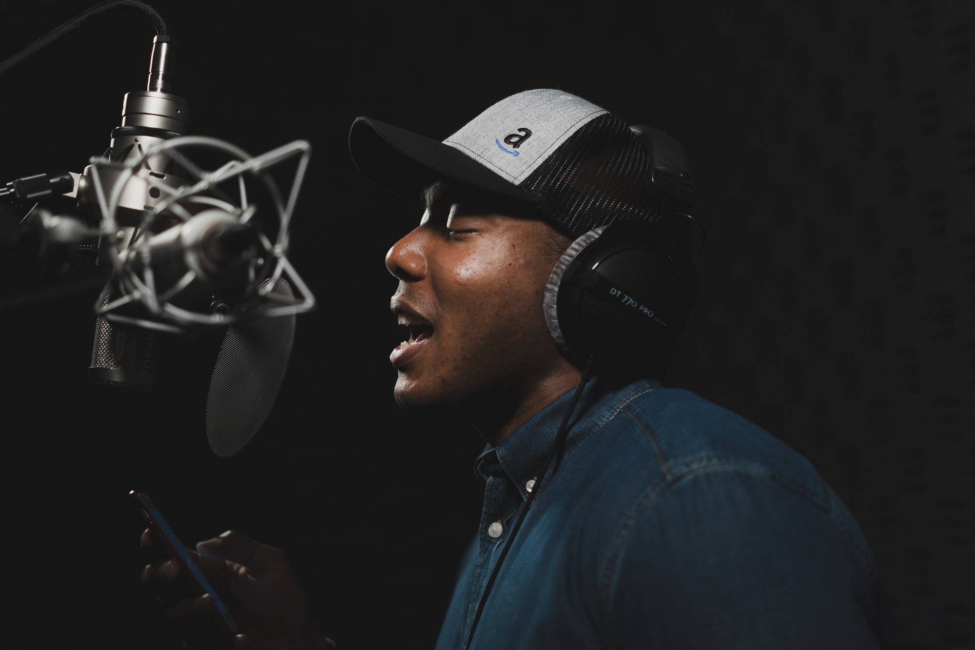 A man sings into a microphone in a recording studio.