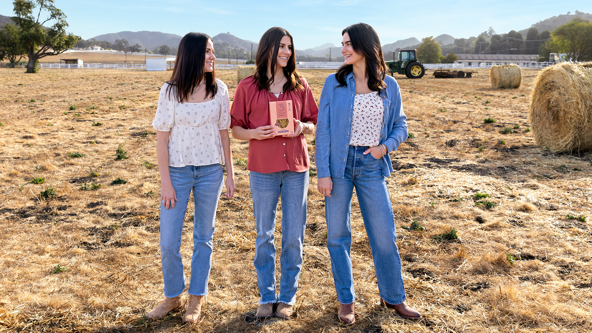 Founders of 3 Farm Daughters standing in a Farm, holding a box of pasta.