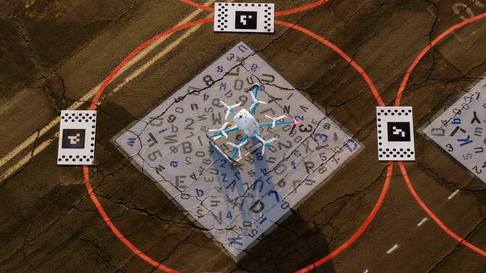 Drone over letter-covered mat surrounded by QR codes