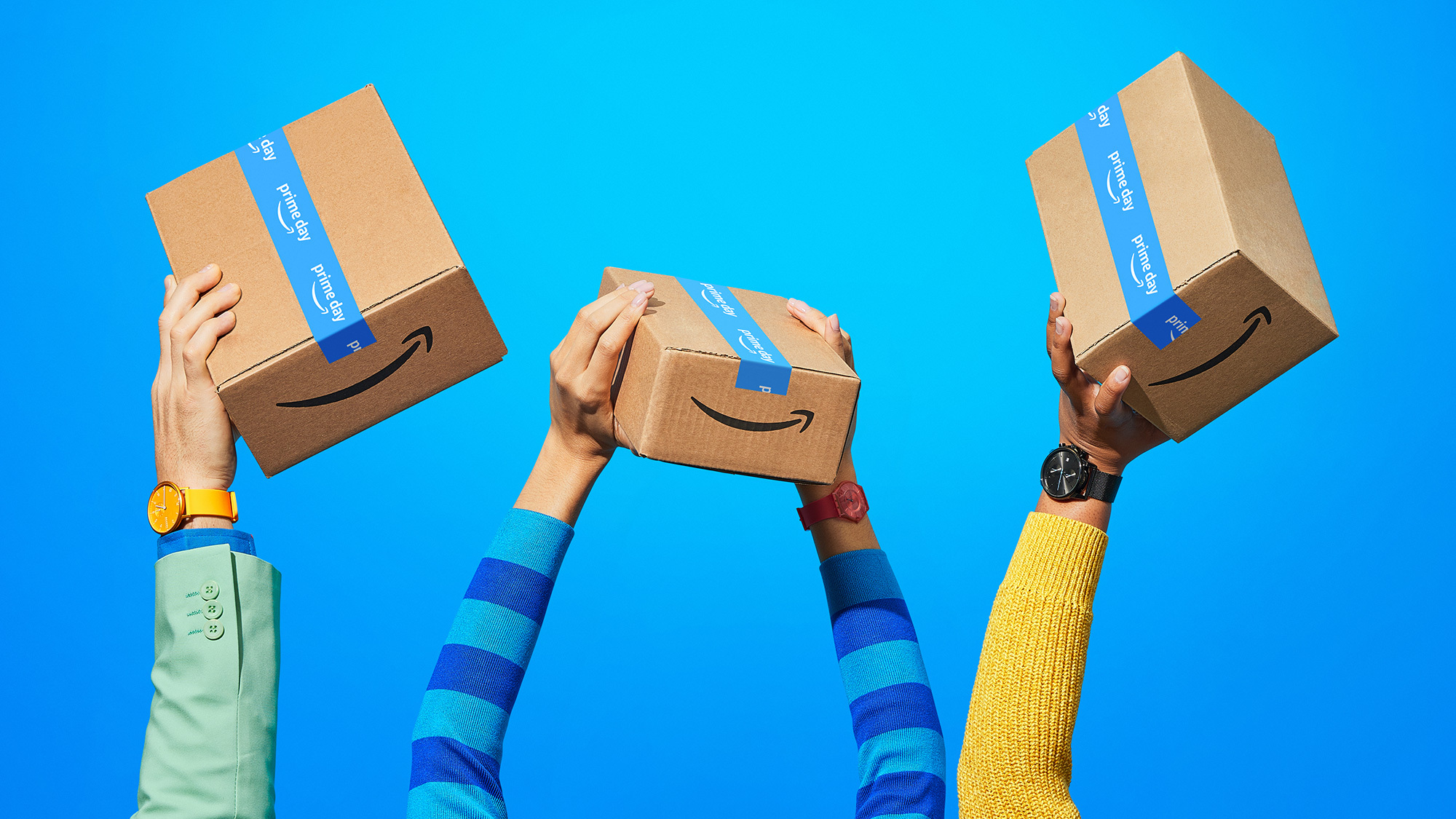 Various human arms hold up Amazon Prime Day boxes.