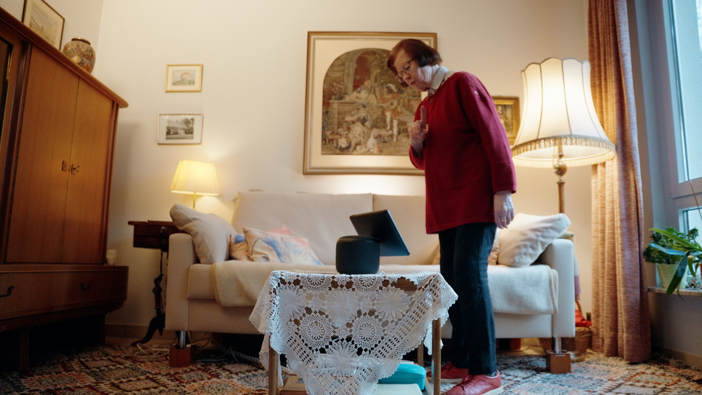 Die 92-jährige Barbara Weber in ihrem Zuhause: Die rüstige Rentnerin trägt einen flotten braunen Pagenschnitt zum roten Pulli und schwarzer Hose.