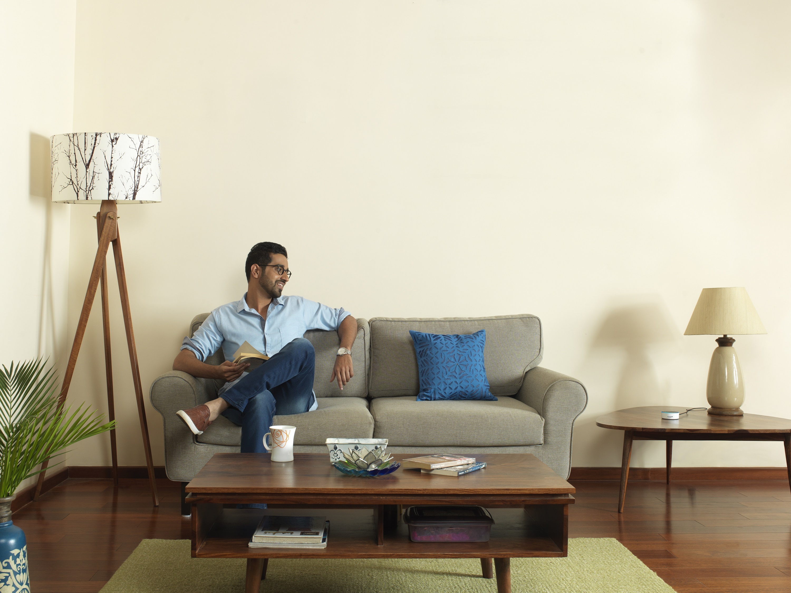A man sits on a sofa in what looks like he is interacting with Alexa