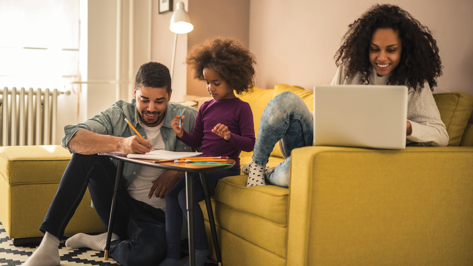 A young man and woman sit on a sofa with a young girl. They all snuggle together as they watch a tv show.