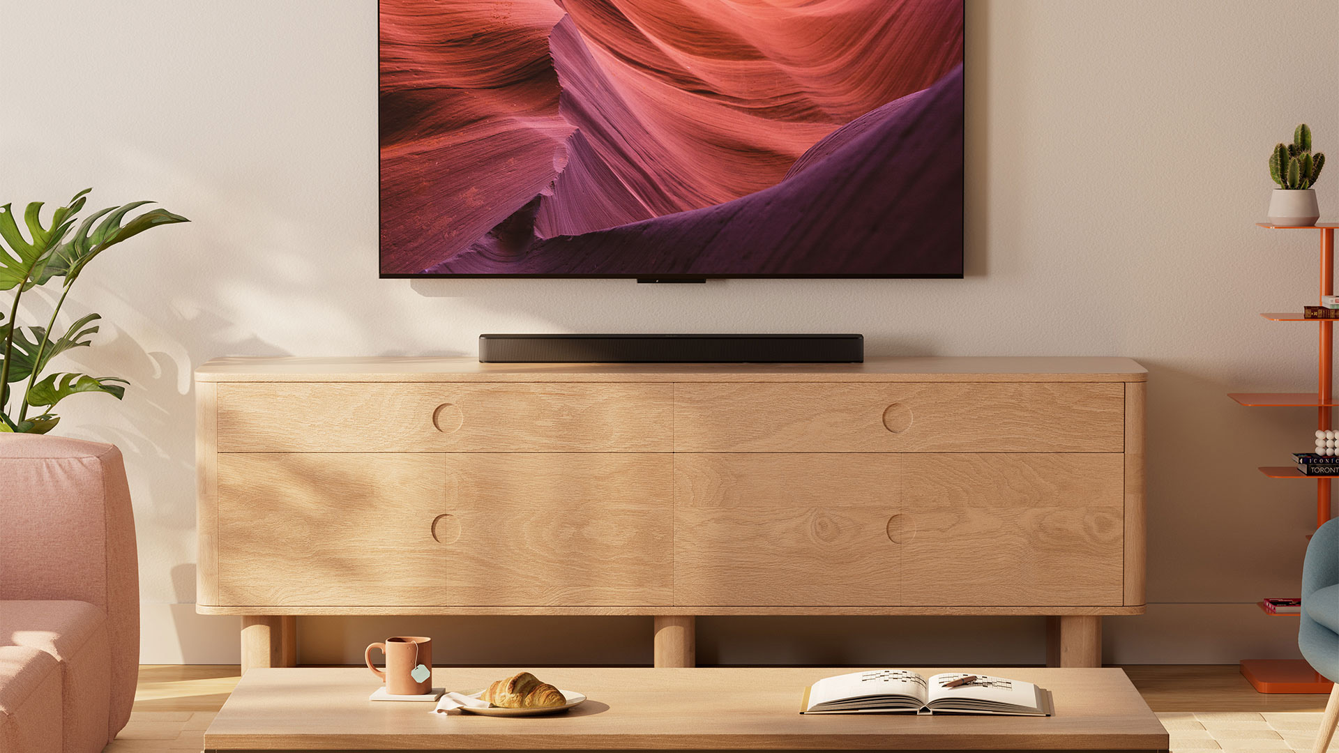 Fire TV Soundbar Plus in einem Wohnzimmer mit Parkett und auf einem Holzgestell. 