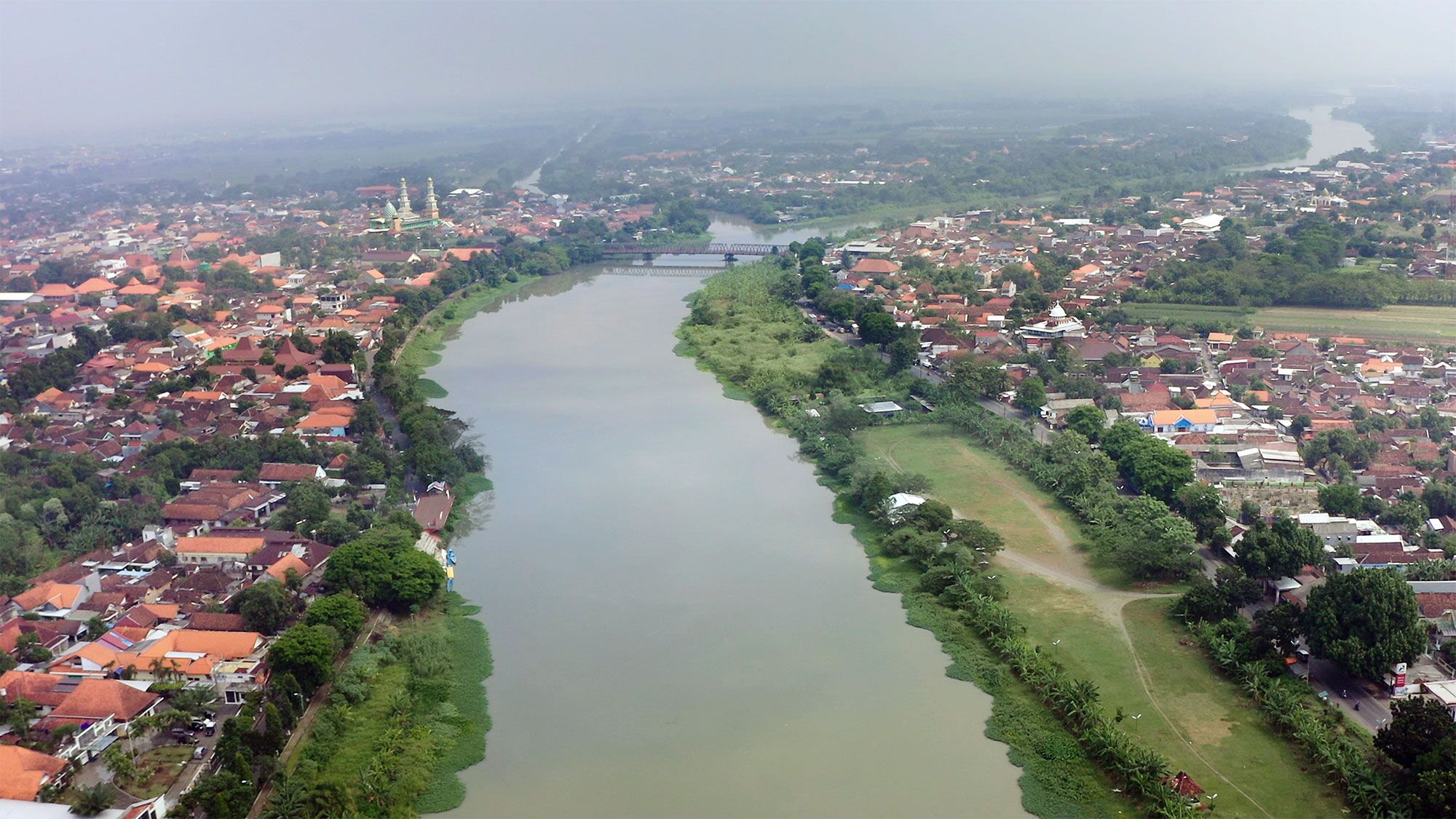Aerial view of city with winding river dividing urban landscape
