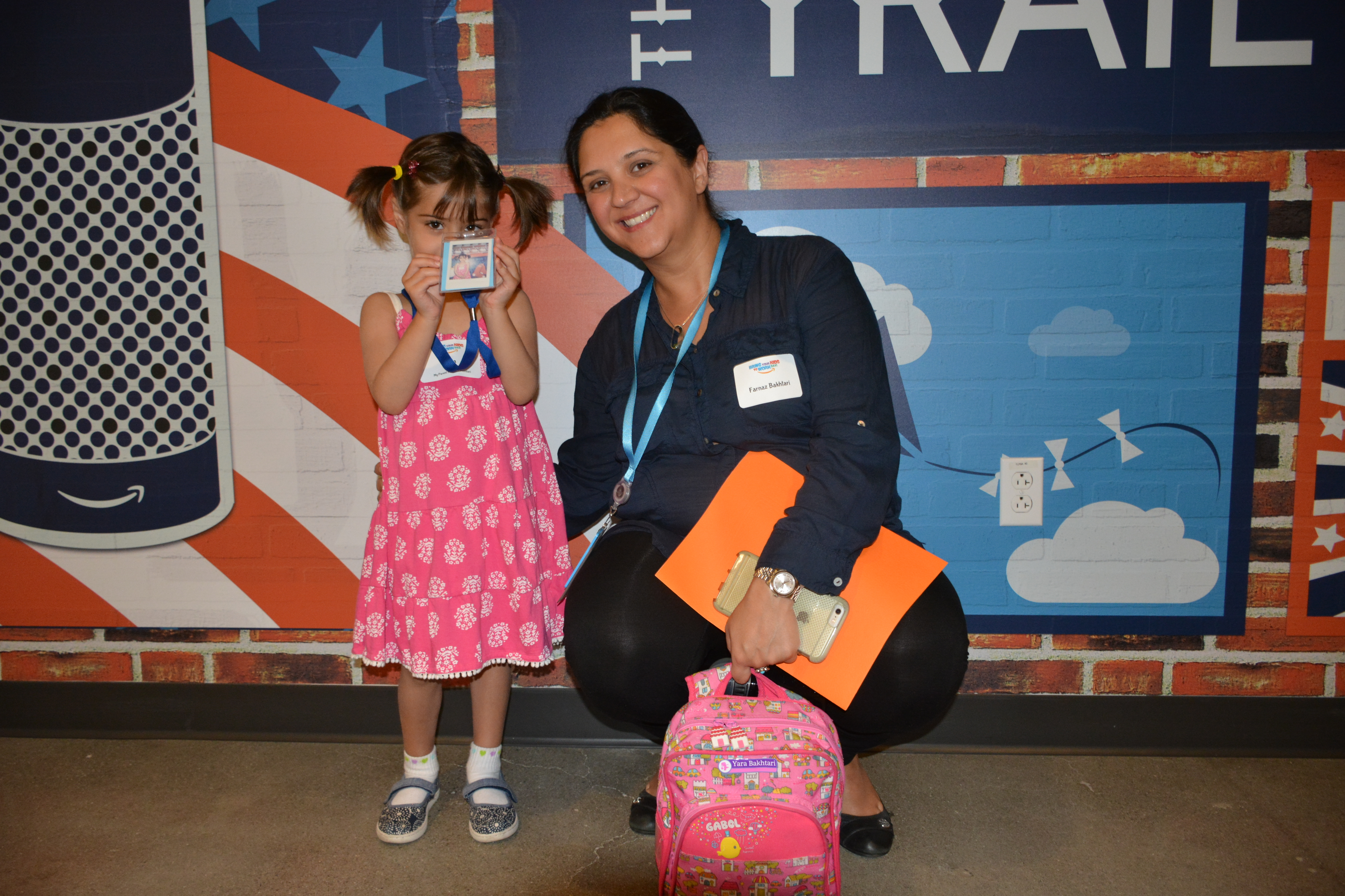 A female Amazon employee crouches down next to her daughter for "Bring your kids to work day."