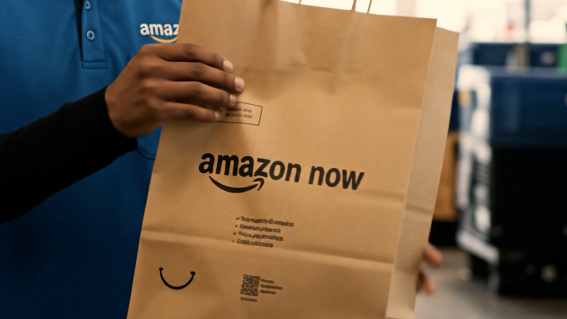 Amazon Now delivery bag held by employee in blue uniform