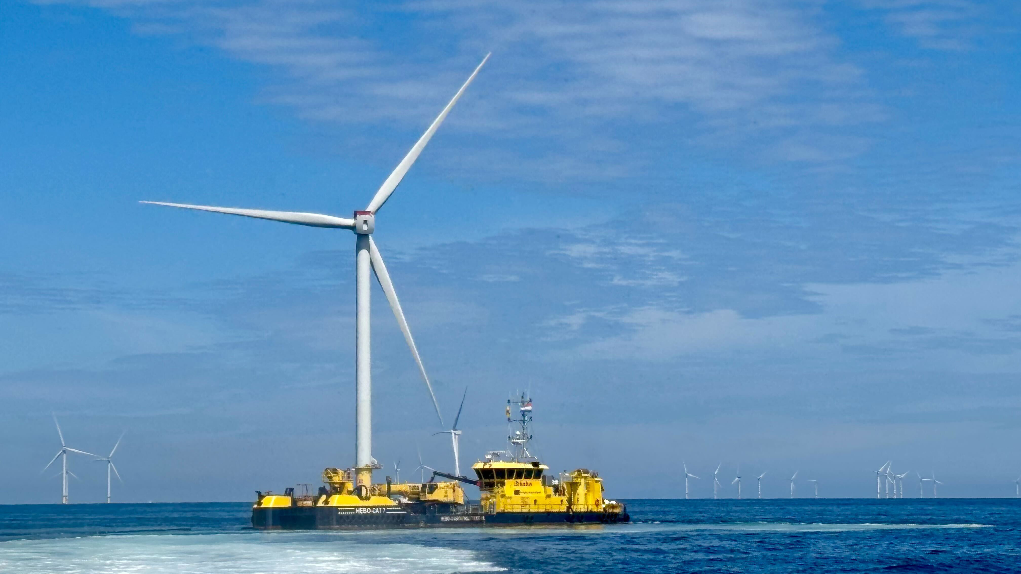 Offshore wind turbine with maintenance vessel in foreground