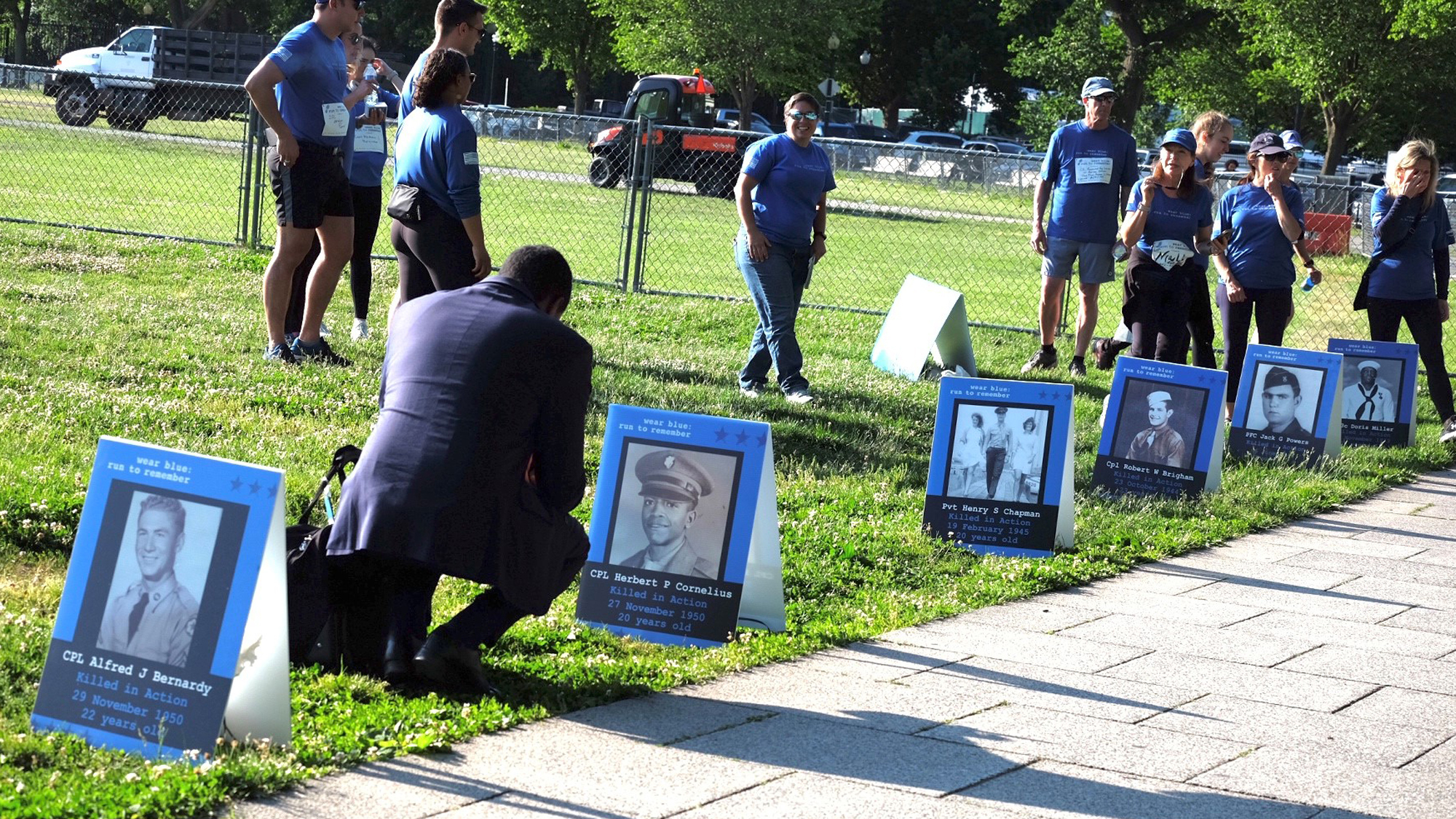 A loved one pays homage to a tribute poster for a fallen service member. 