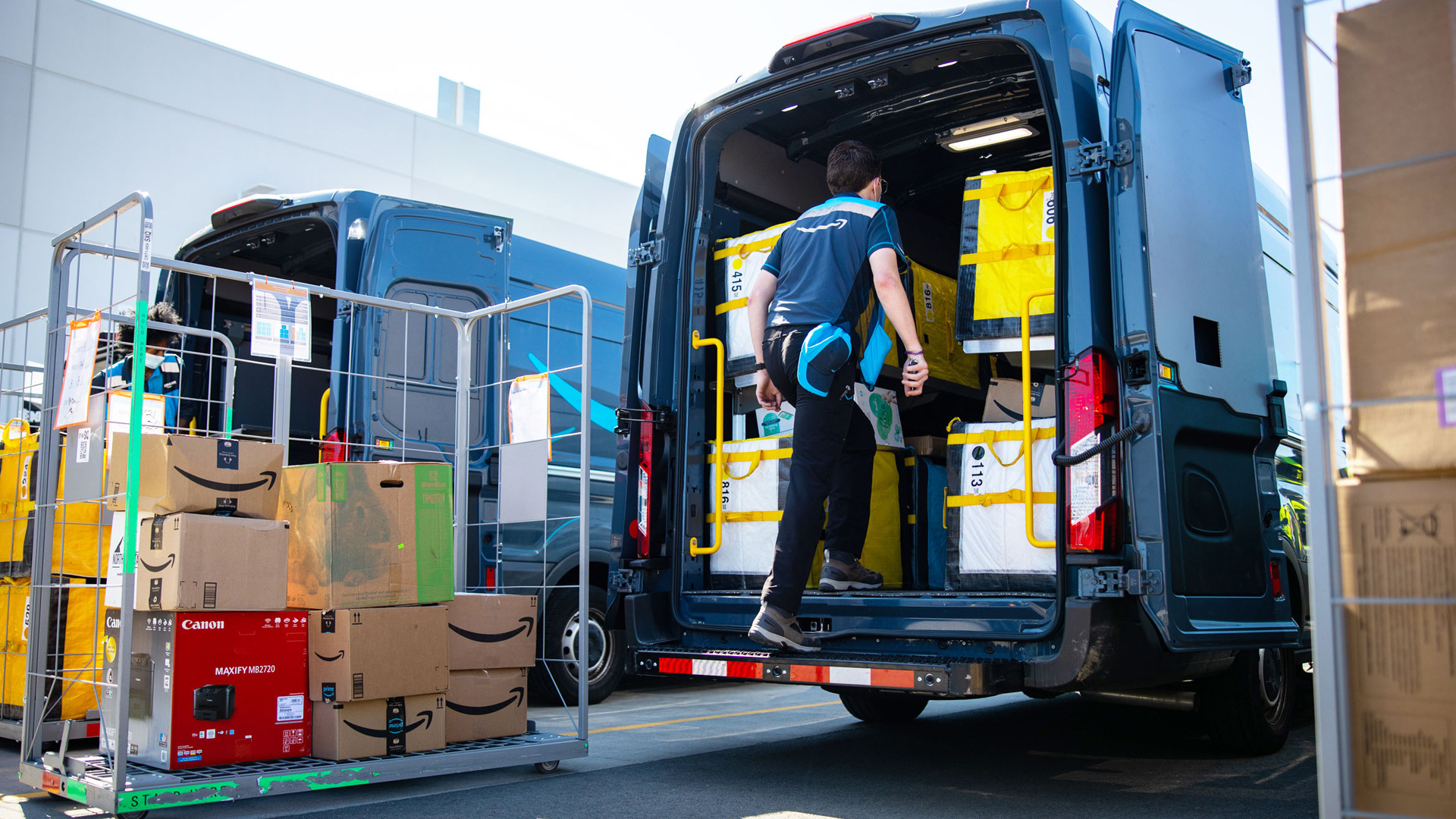 An Amazon delivery driver loads boxes into a delivery van.