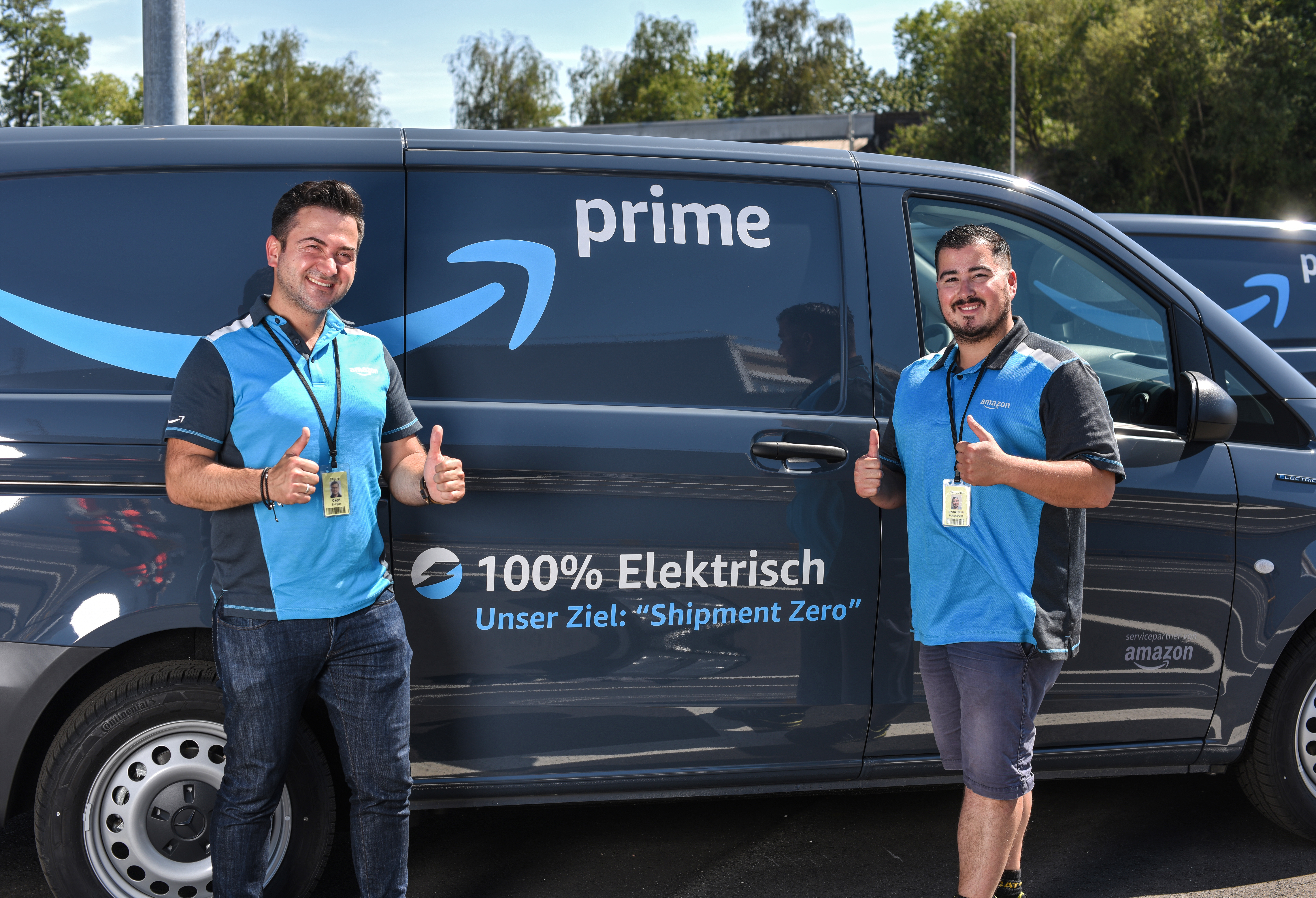 2 junge Männer in blauen Amazon Shirts vor einem Prime Lieferfahrzeug.