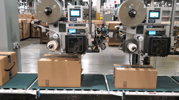 Amazon packages are being stamped with customer addresses as they move along a conveyor belt.