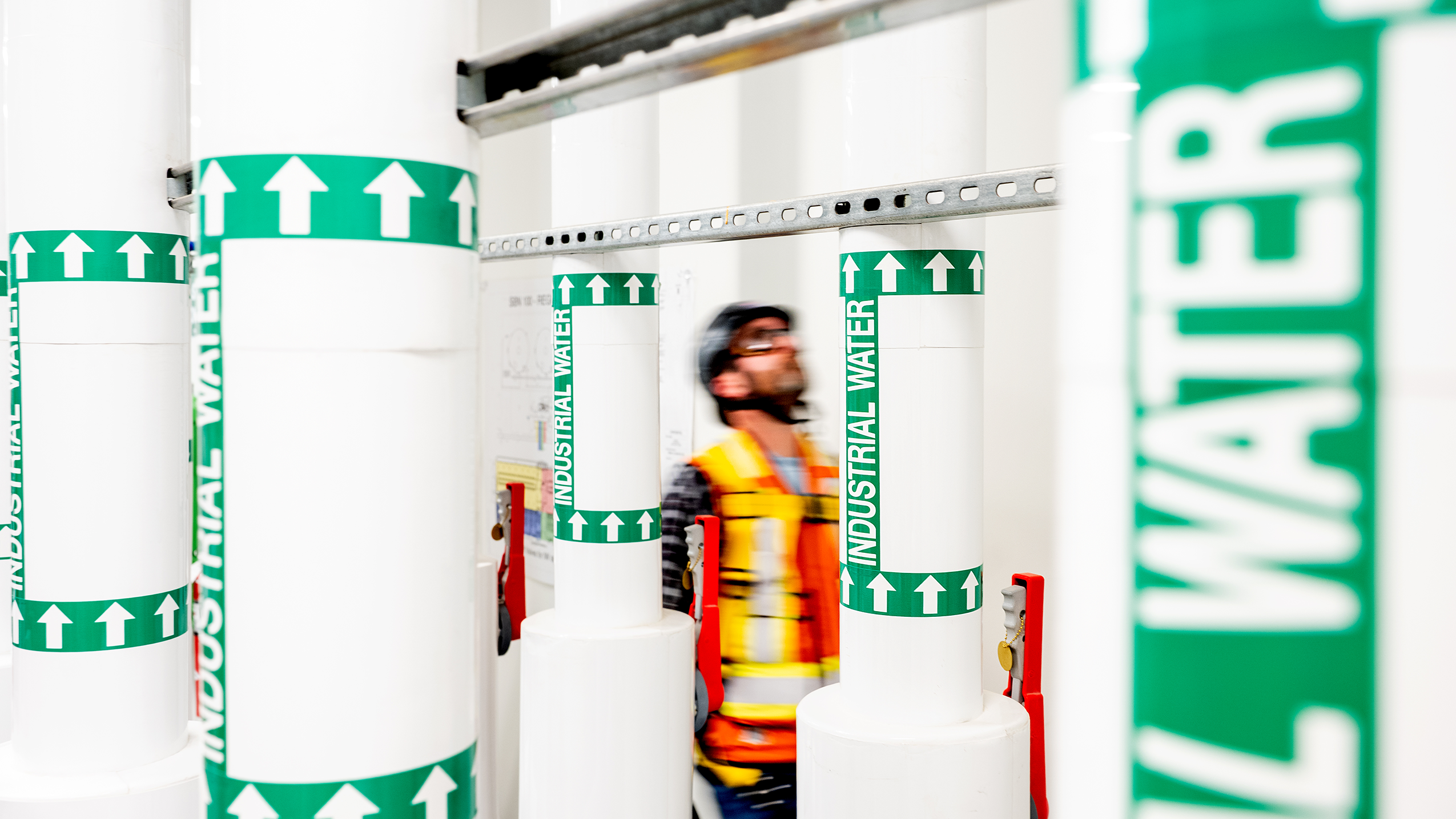 A technician standing between water pipes.