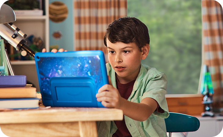 Young boy using a Kindle at his desk in his bedroom