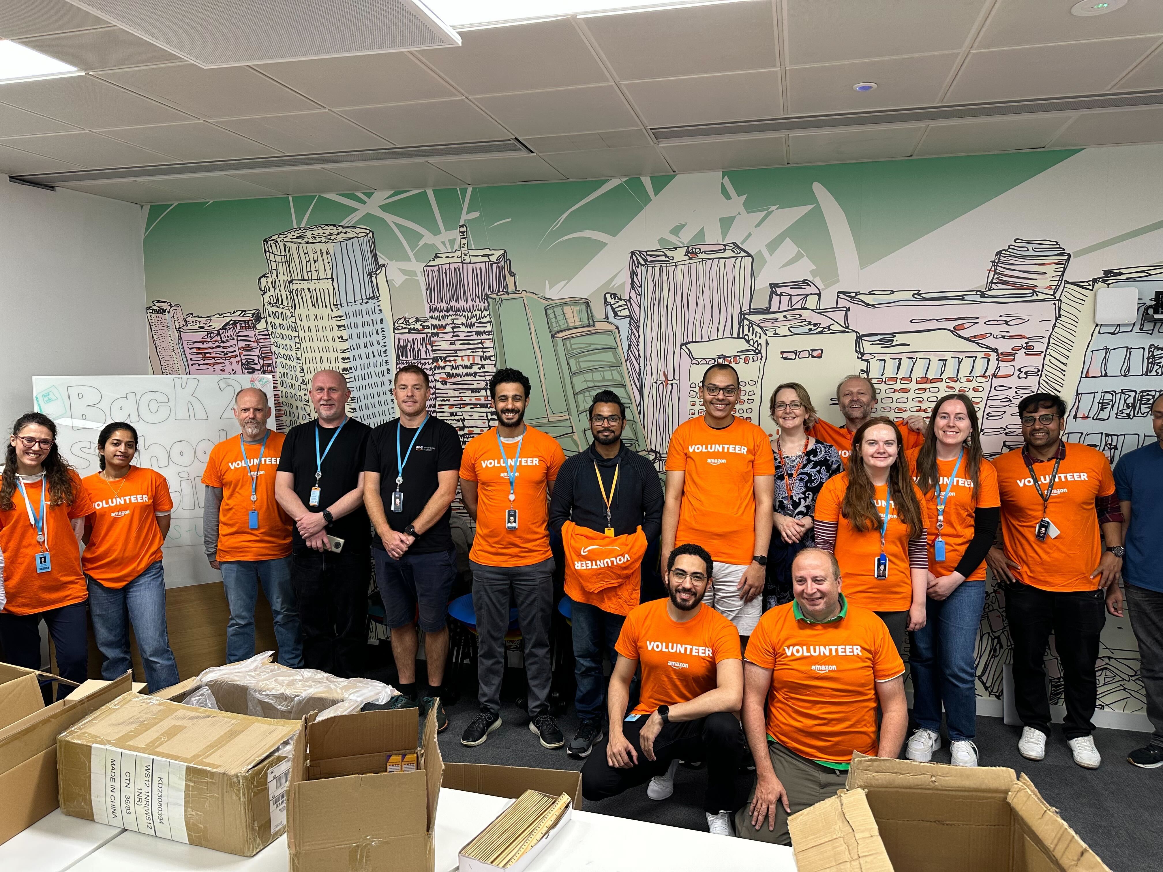A group of Amazon employees take a break from packing back to school backpacks for children