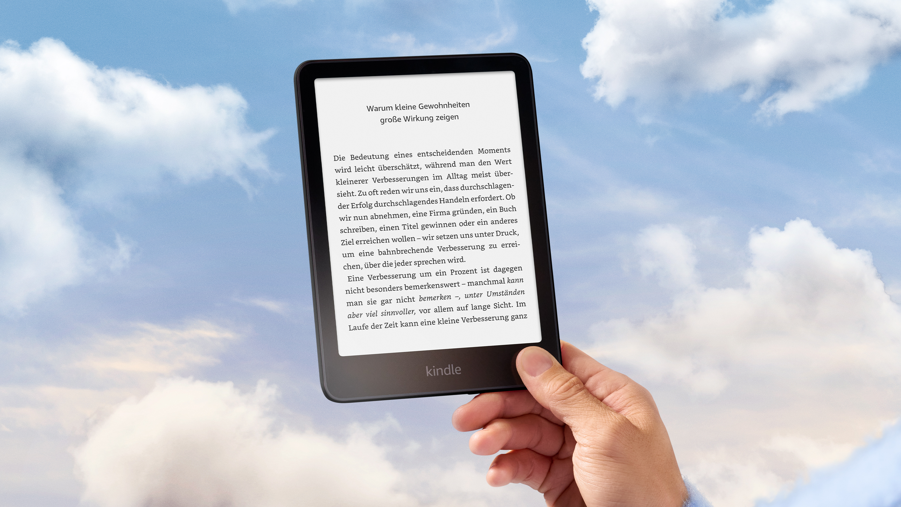 Eine Hand hält einen Kindle Paperwhite vor blauem Himmel mit weißen Wolken.