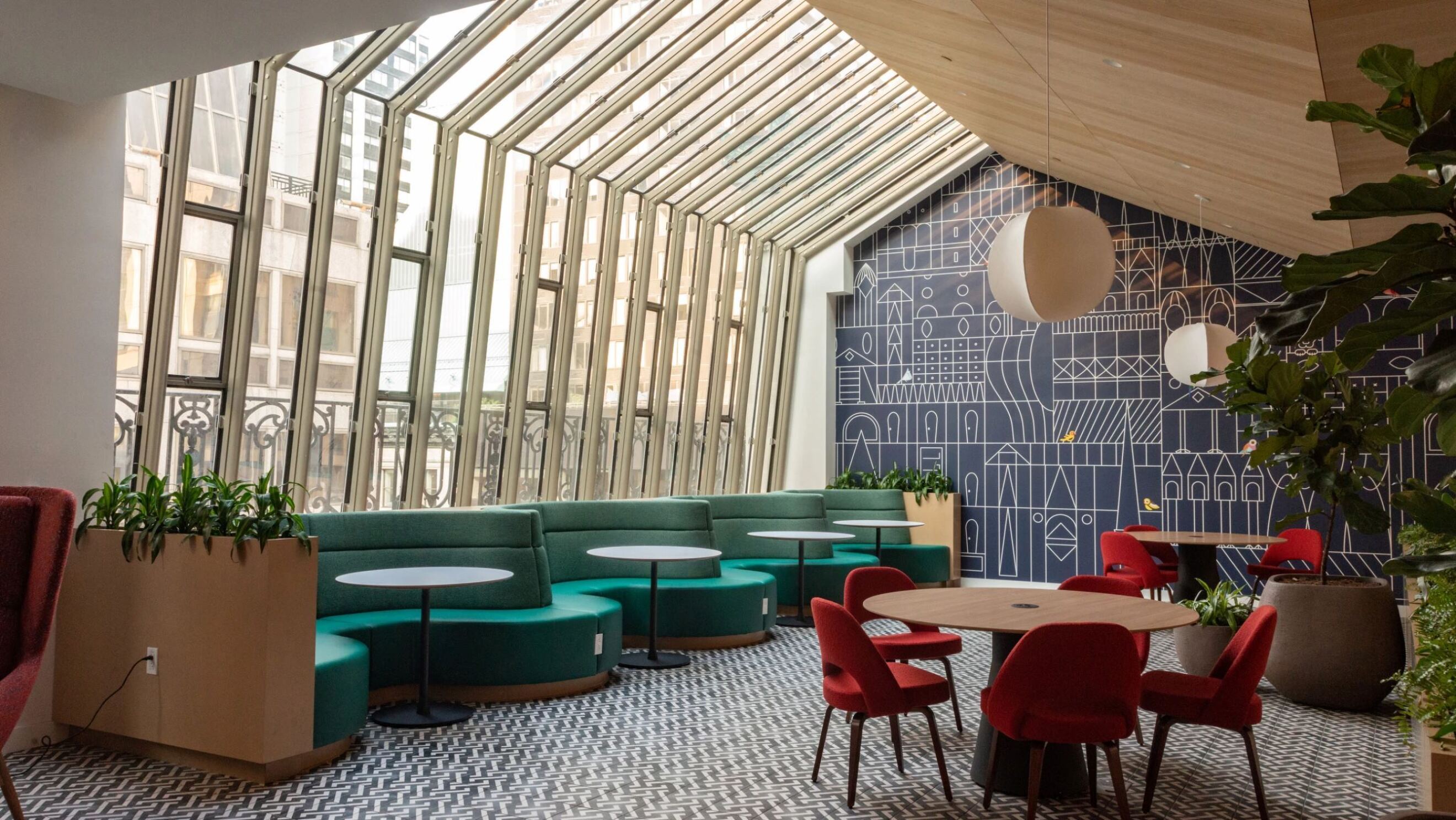 屋根の半分と壁からなるガラス窓から外光が差している、緑色の曲線のソファや、赤い椅子、いくつかのテーブルなどが設置されている。