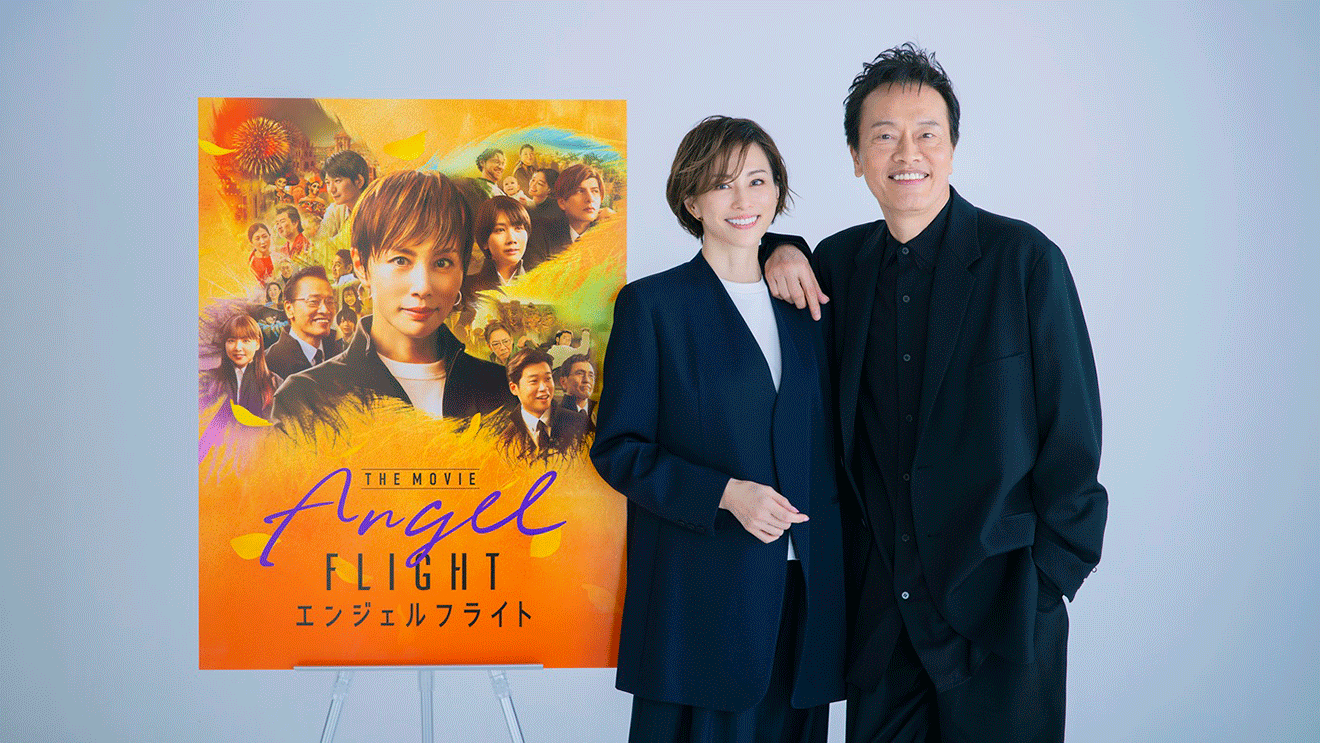 ブルーグレーの壁を背景に立つ、米倉涼子氏と遠藤憲一氏。米倉氏の左肩に、遠藤氏が腕をのせている。2人の左側に、「エンジェルフライト」のキービジュアルアートが置かれている。