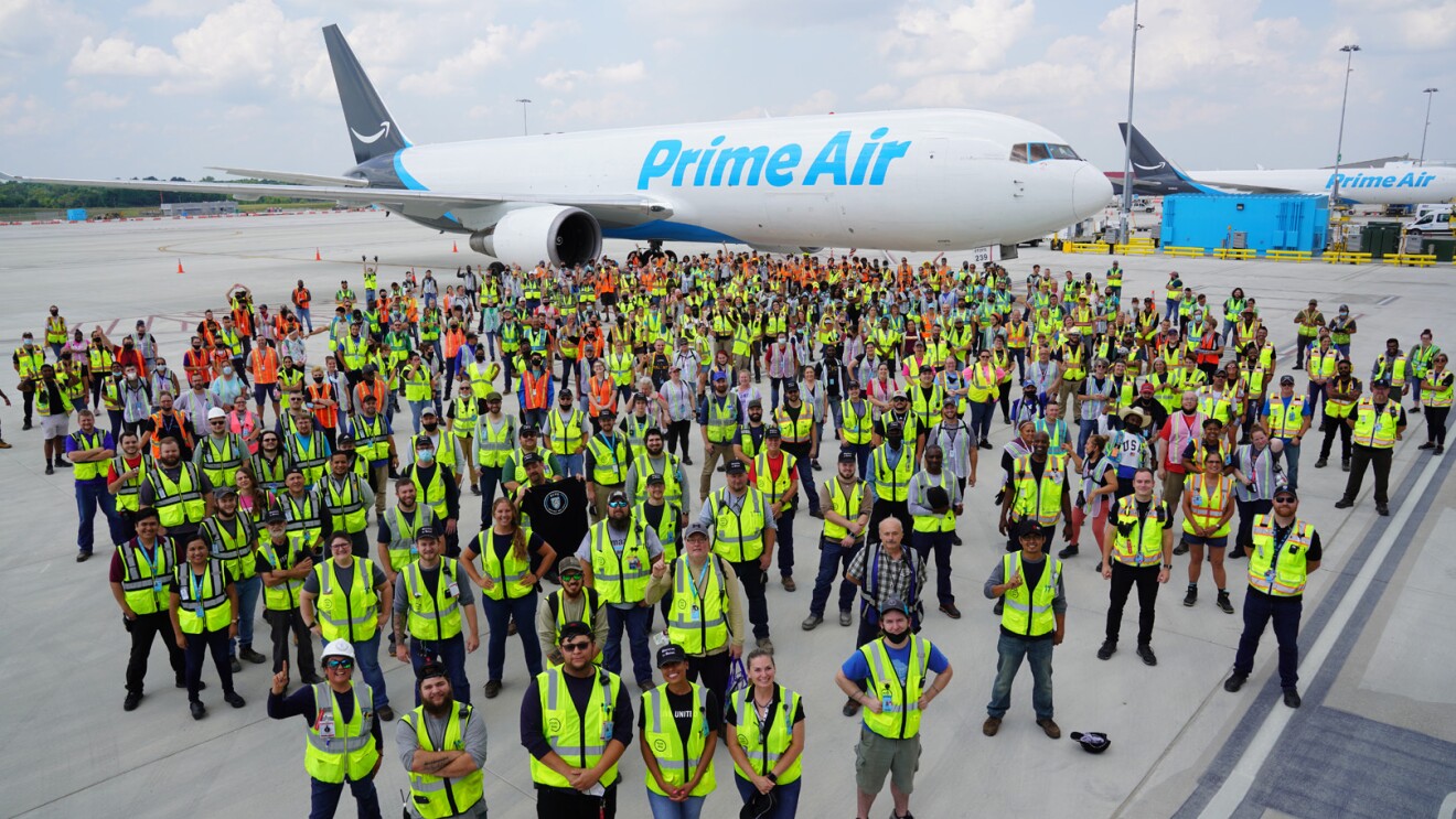 An image of more than 100 employees wearing their safety vests while standing in front of a Prime Air plane at the Kentucky Air Hub.