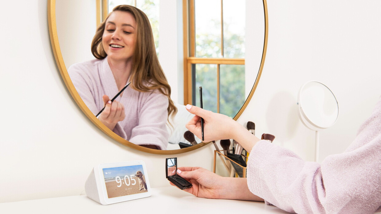 Mujer maquillándose en un tocadotr donde está un echo con Alexa. 