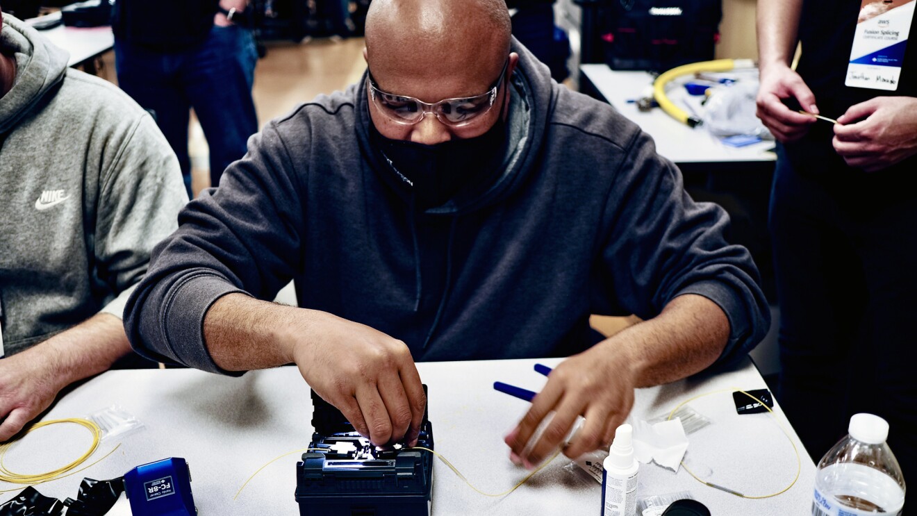 An image of a man working on a piece of technology hardware while wearing safety glasses.