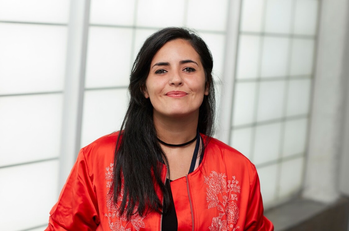 An image of Rocio wearing an orange jacket and smiling.