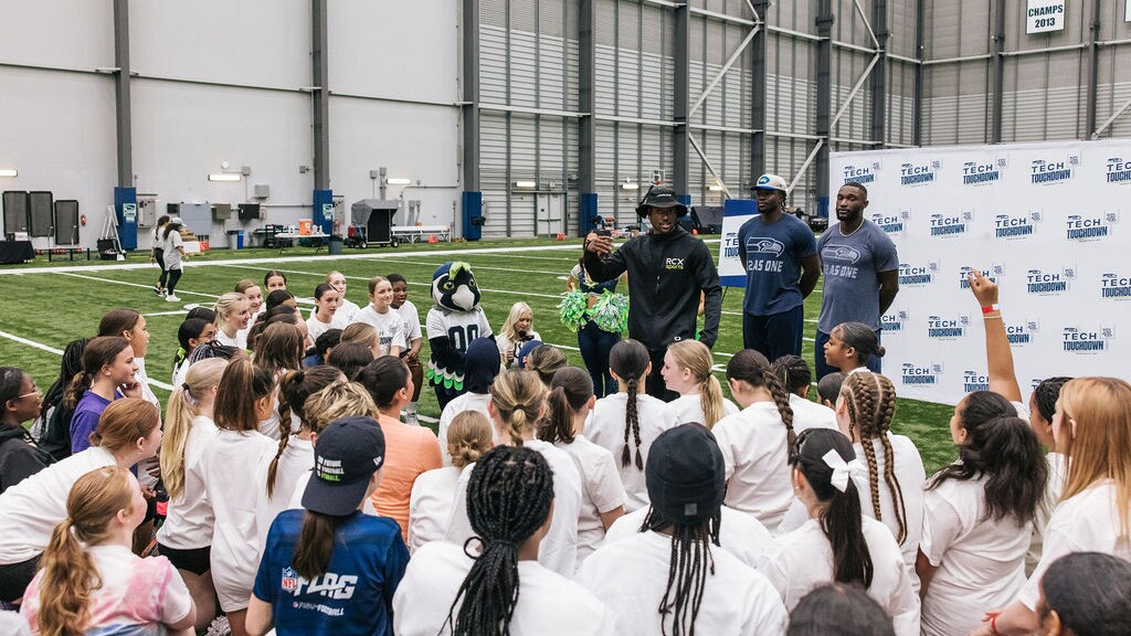 NFL players addressing group of young athletes at training facility