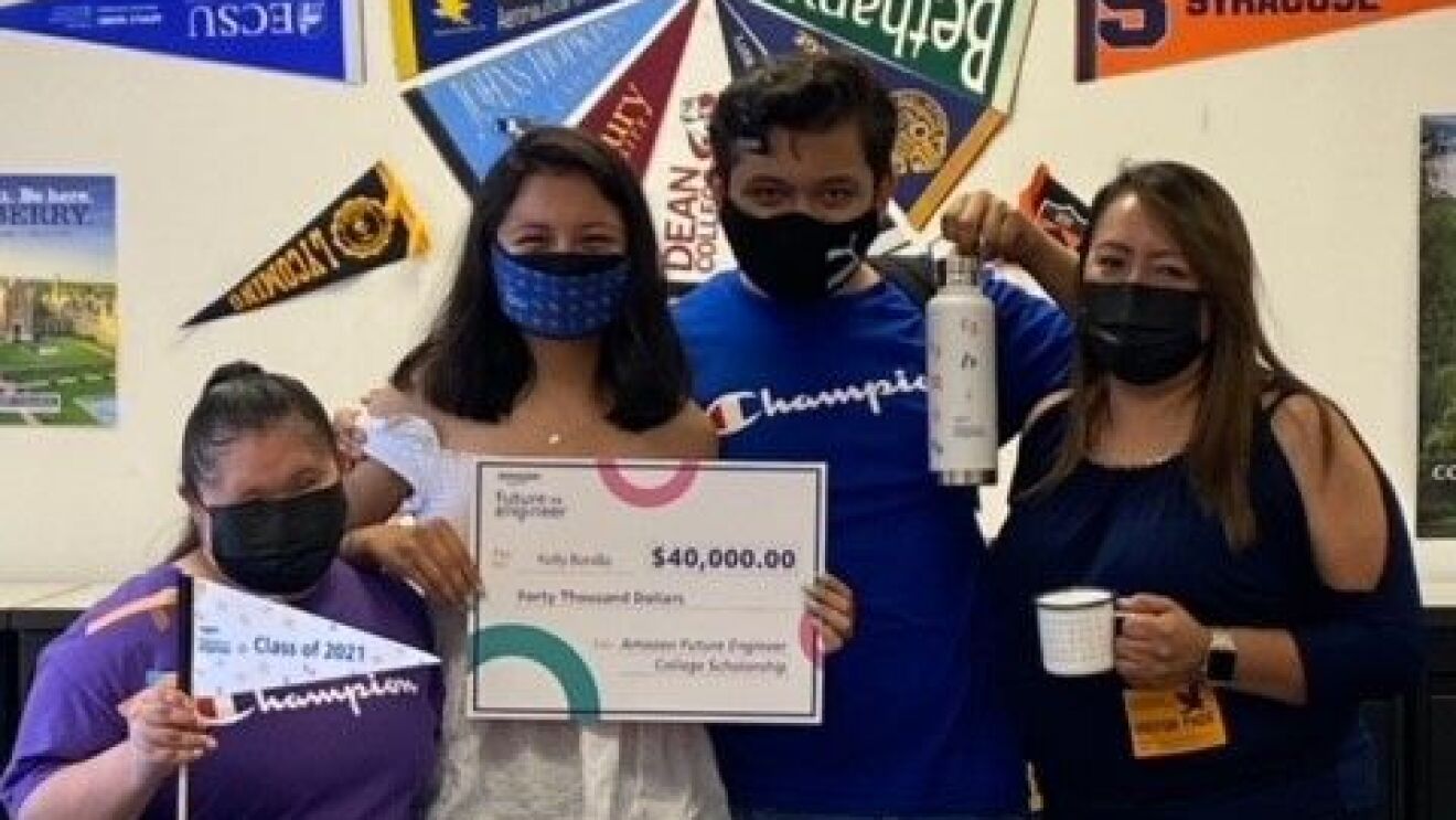 An image of an Amazon Future Engineer scholarship recipient with her family. She is holding check for the scholarship.